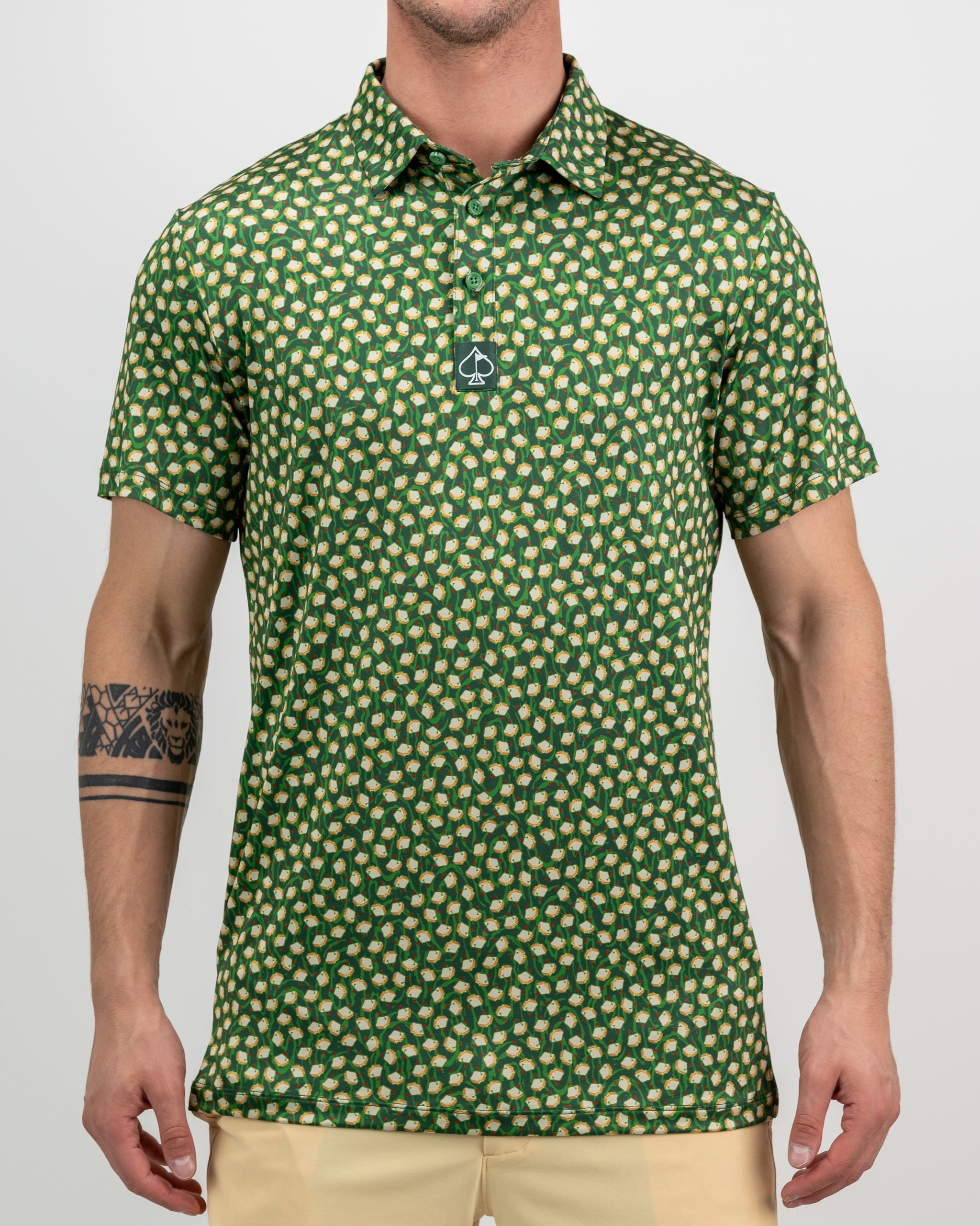 Men's green golf polo shirt with a bold, repeating pattern of golf balls and clubs, featuring a small spade logo on the ch...