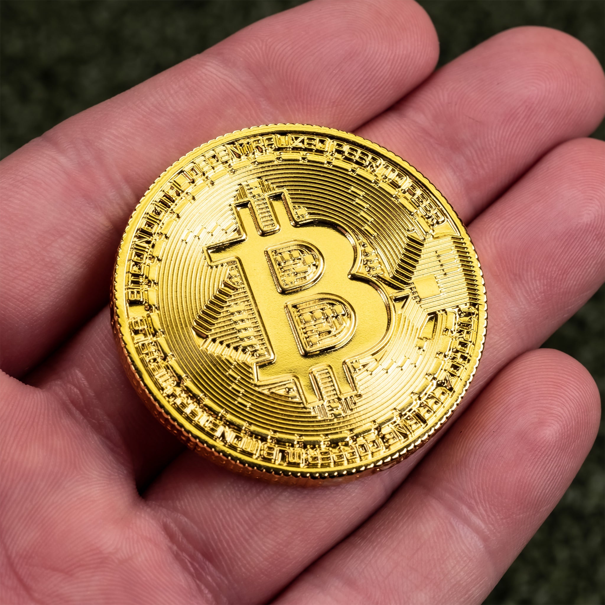 Bitcoin ball marker held in hand, featuring a gold Bitcoin design on a circular metal base.