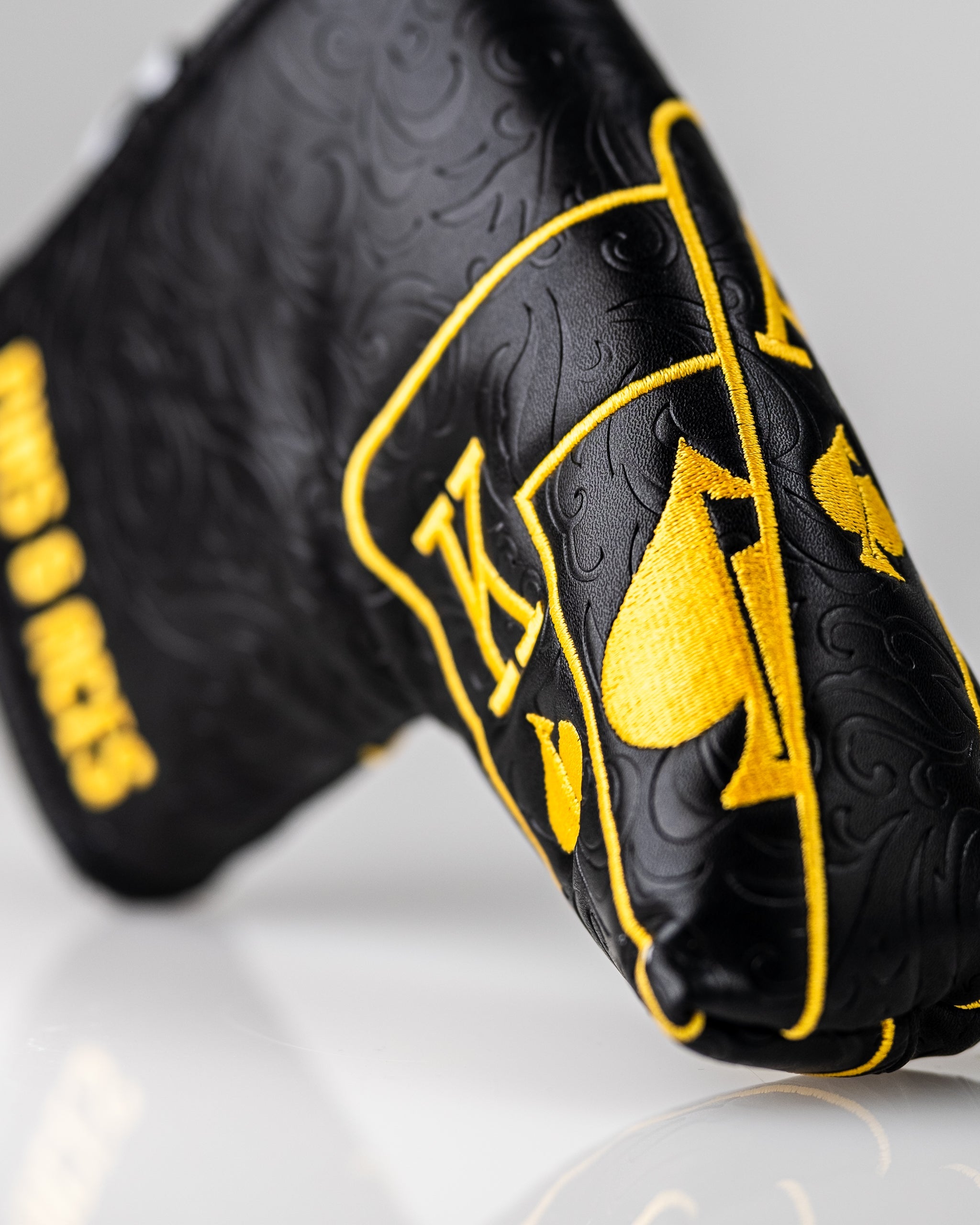 Black and gold Ace of Spades blade putter cover with a sleek design and detailed emblem.