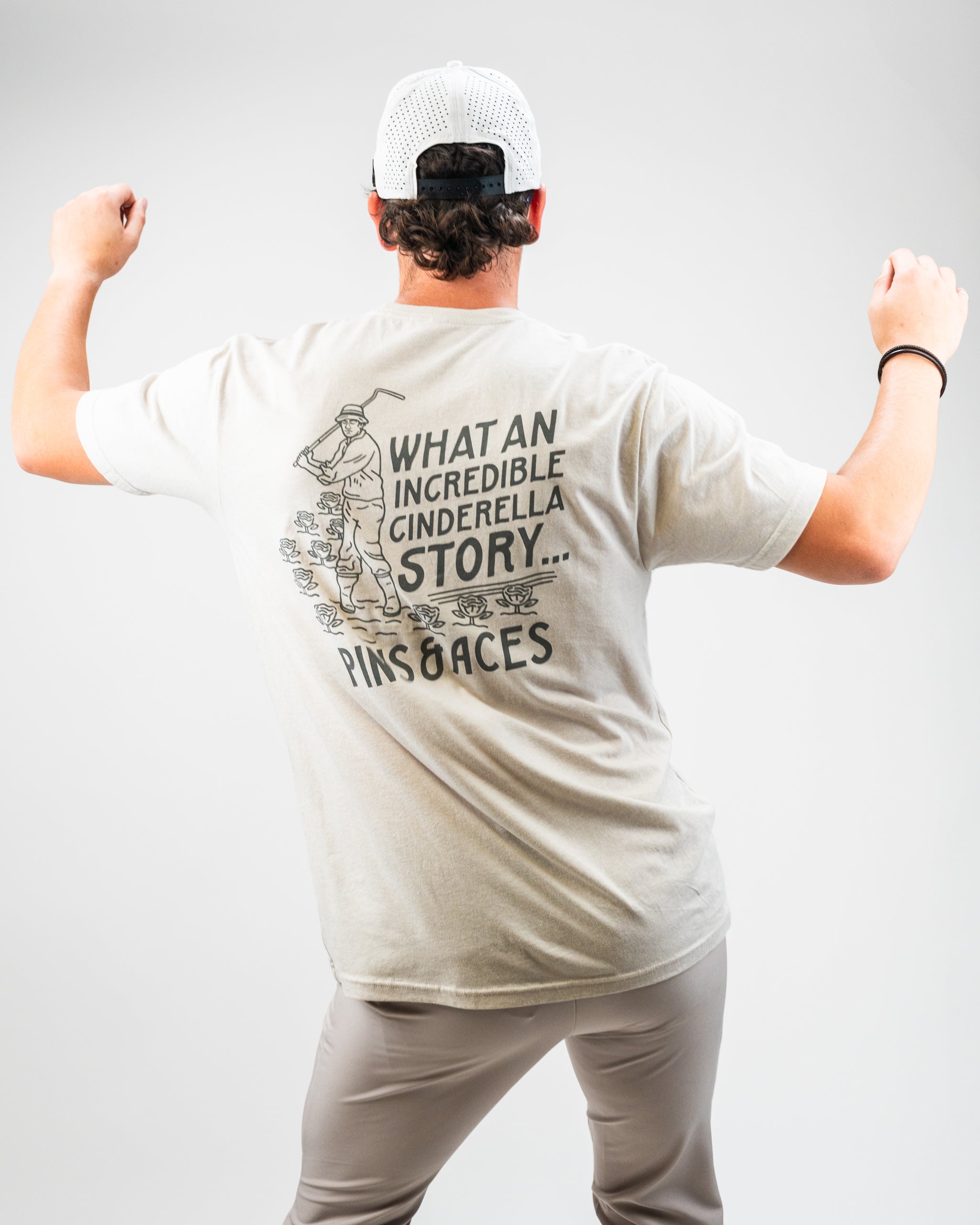 Light gray tee shirt featuring a golfer graphic and the text "What an Incredible Cinderella Story" on the back.