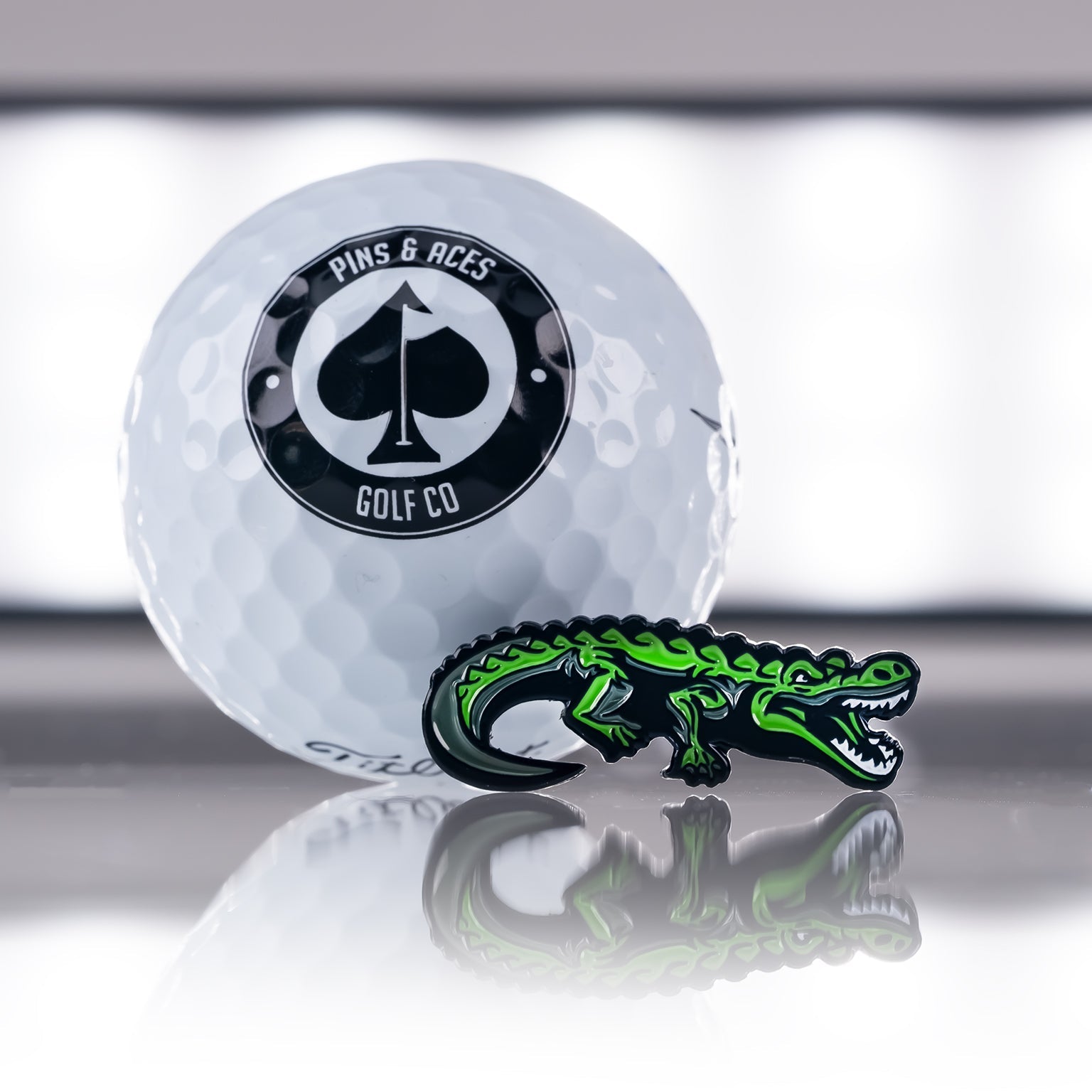 Crocodile-shaped golf ball marker with a reflective surface.