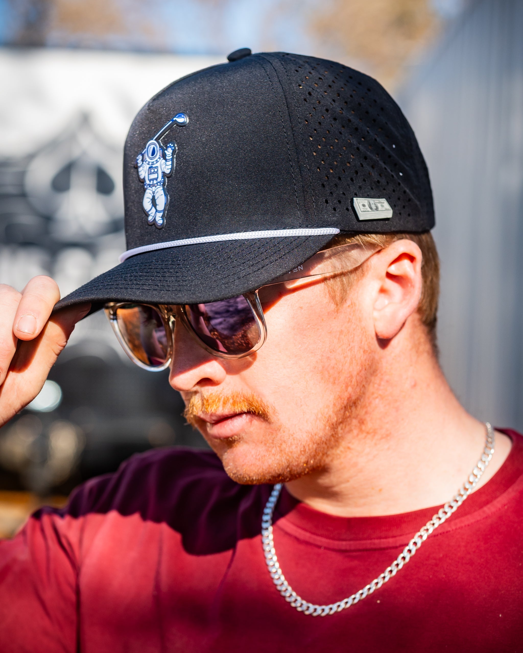 Perforated black rope hat for golfers featuring a space-themed design.