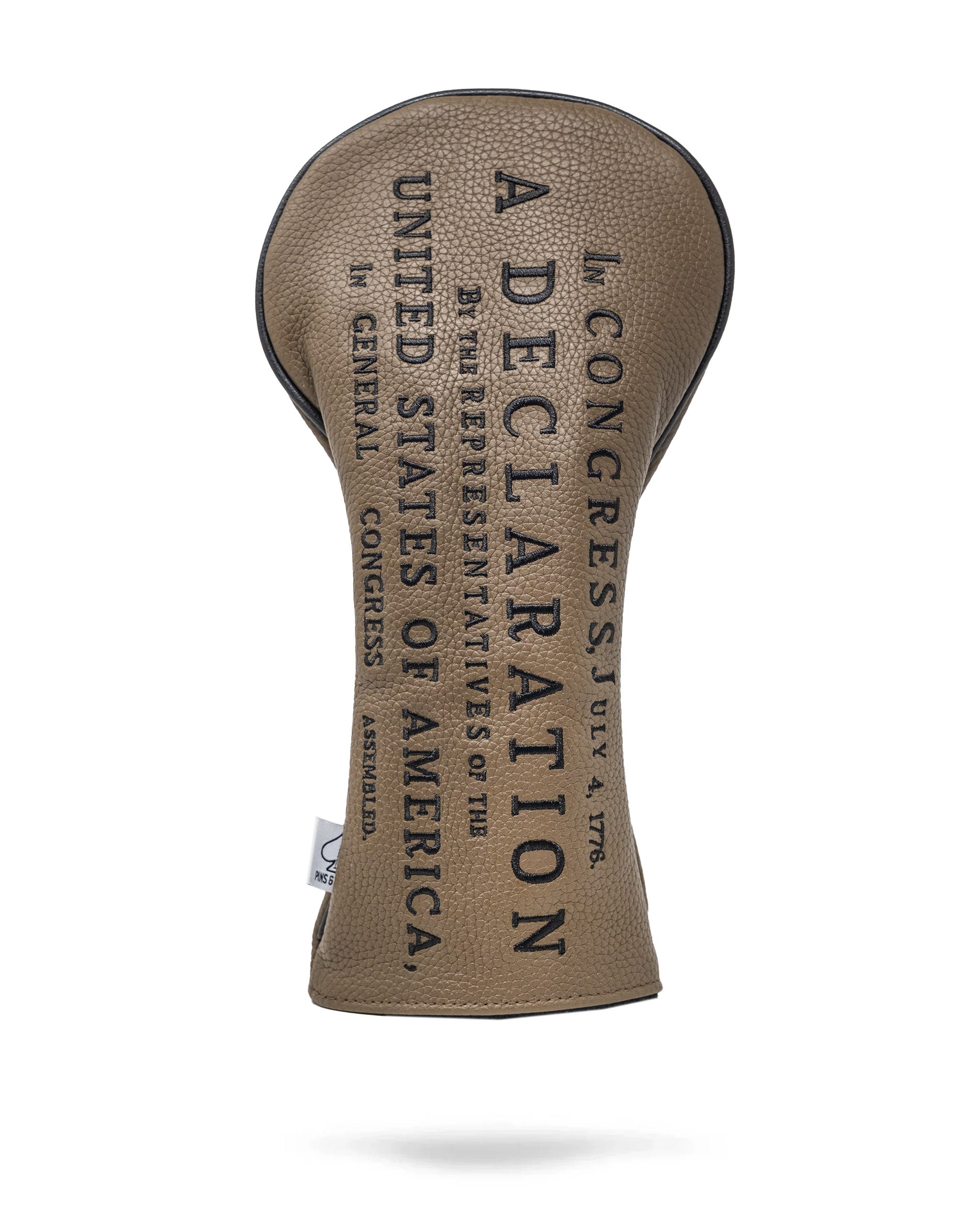 Golf driver headcover with beige textured fabric and black embroidered text reading Declaration by Pins and Aces.