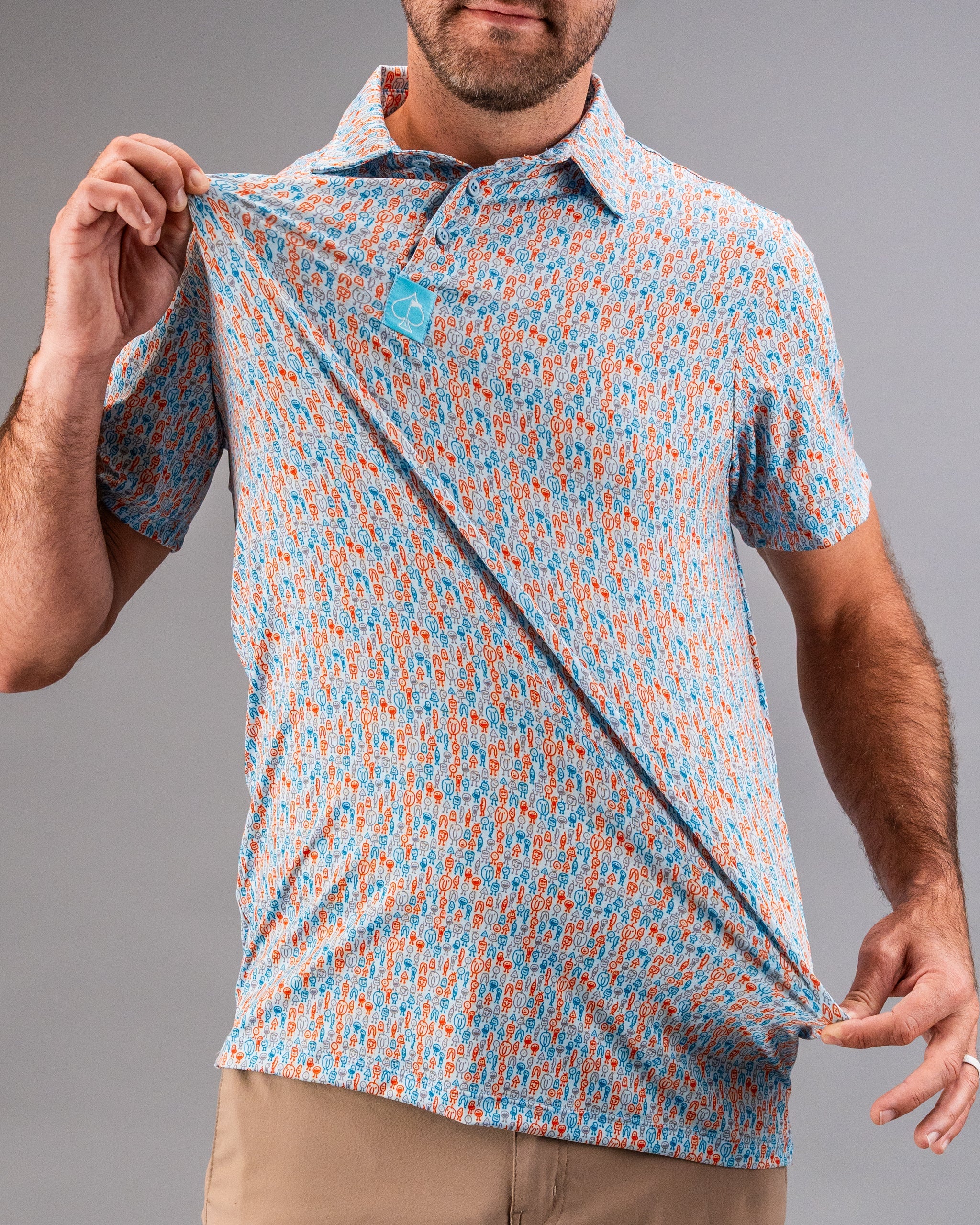Man holding a colorful, patterned golf shirt in blue, orange, and white, with bold, playful details for standout golf style.