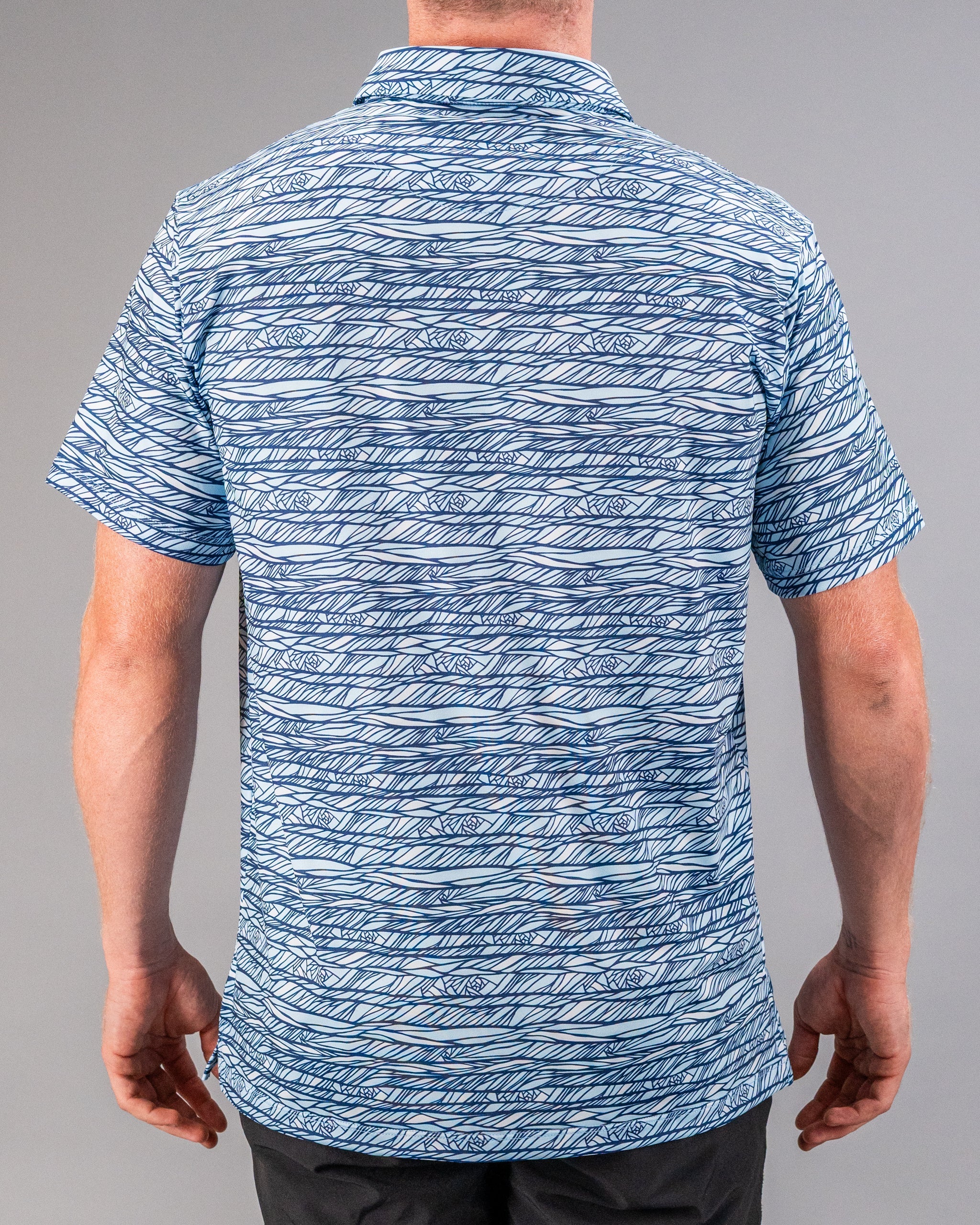 Blue and white patterned golf shirt with abstract line design, short sleeves, and a collared neckline.