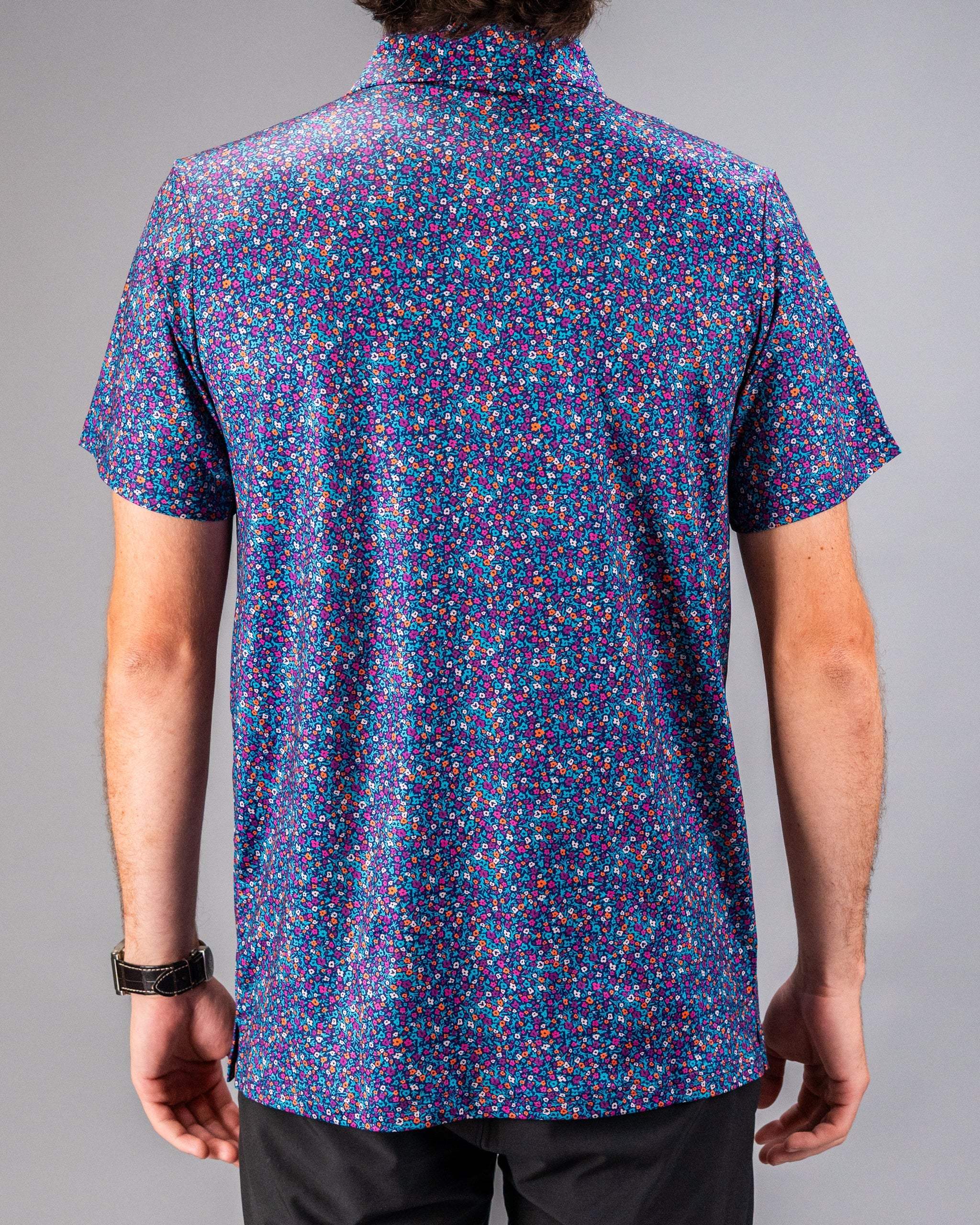 Men's short-sleeve golf shirt featuring a vibrant lavender floral pattern on a dark background, ideal for stylish play.