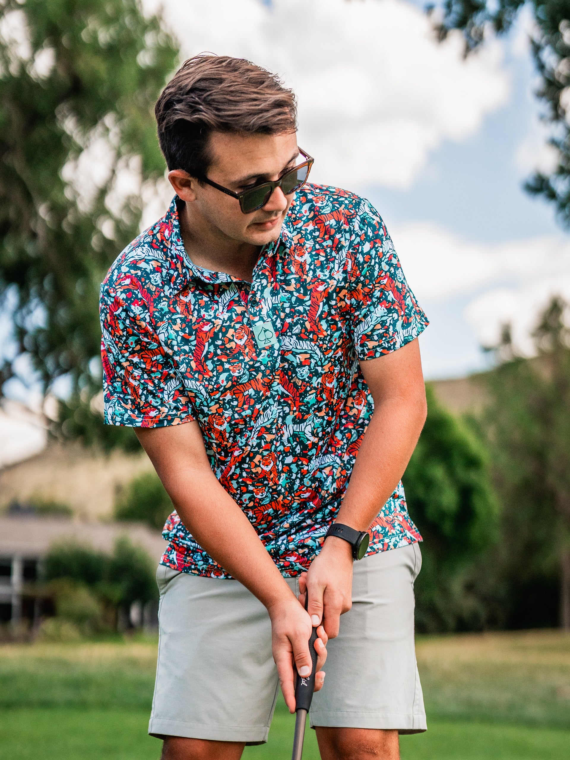 Bold Tiger Shatter Teal golf shirt featuring a vibrant pattern, worn by a golfer preparing to putt on the course.