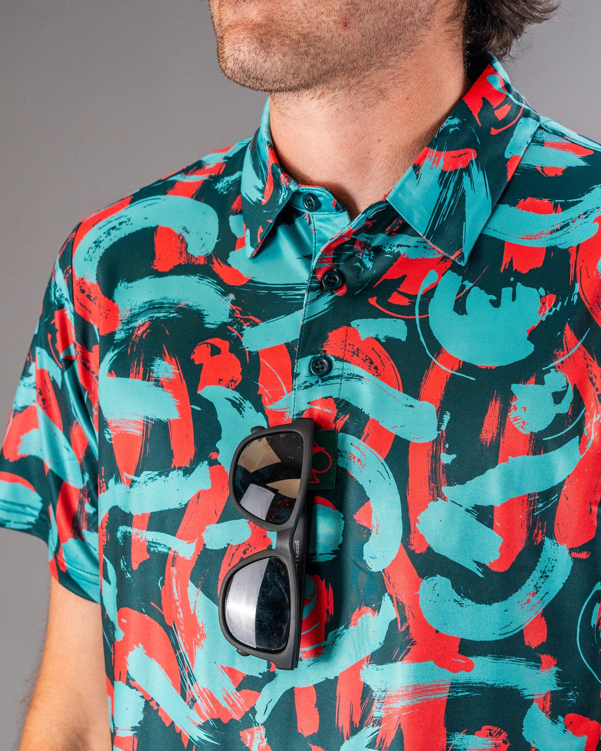 Bold golf shirt featuring a vibrant coral and teal paint stroke pattern, perfect for making a statement on the course.