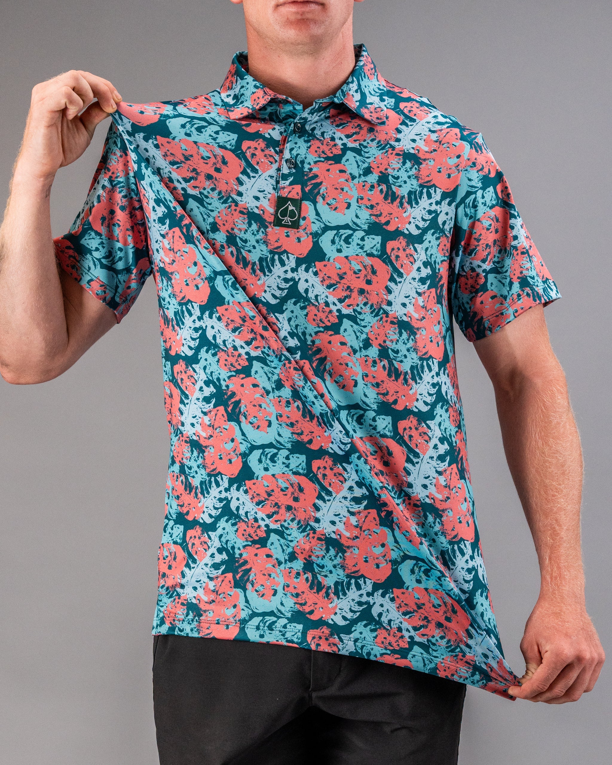 Bright tropical print golf shirt with red, blue, and teal leaves, featuring a collar and button-up front for bold golfing ...