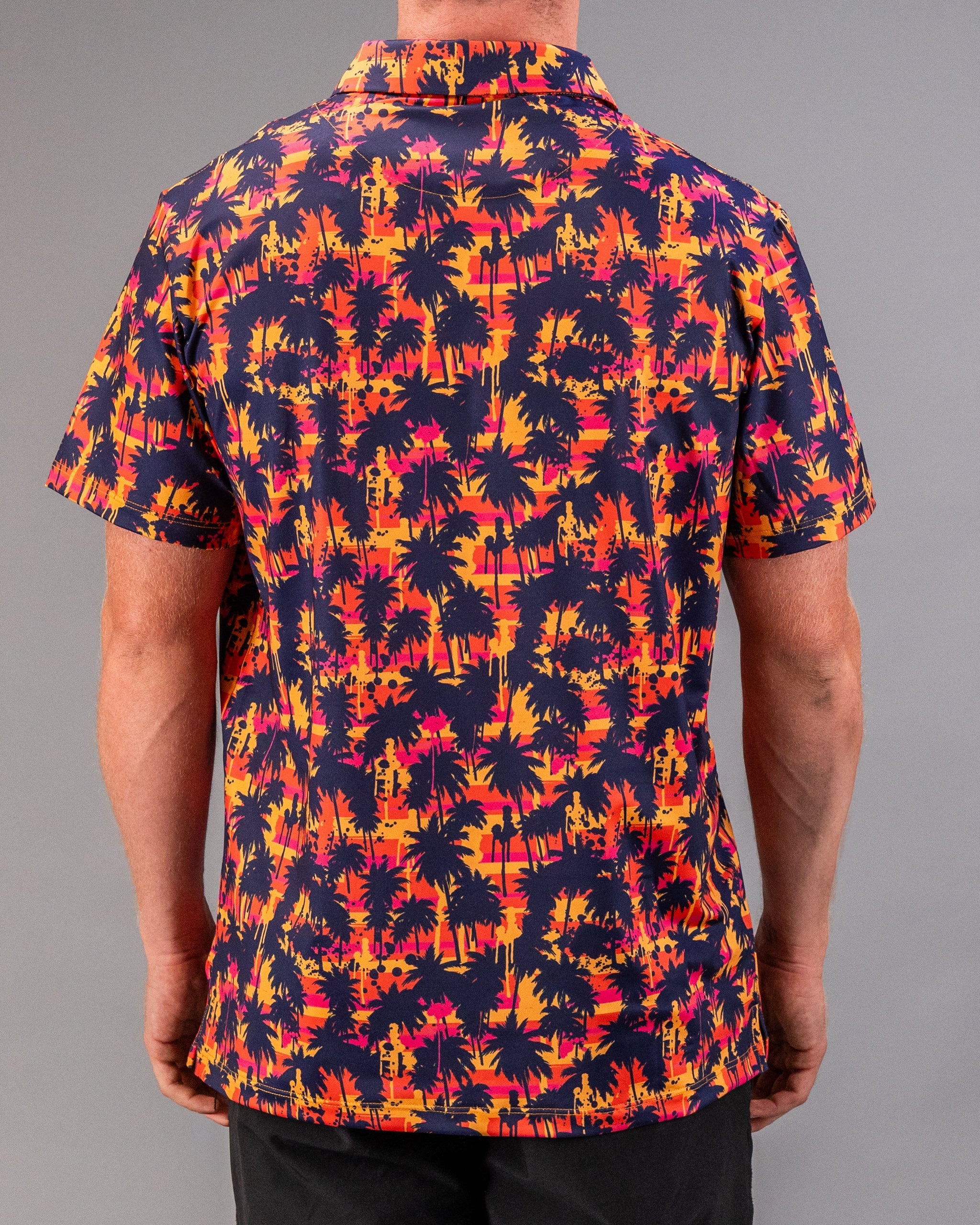 Men's tropical-themed golf shirt with vibrant orange, pink, and navy palm tree print, perfect for bold golf style.