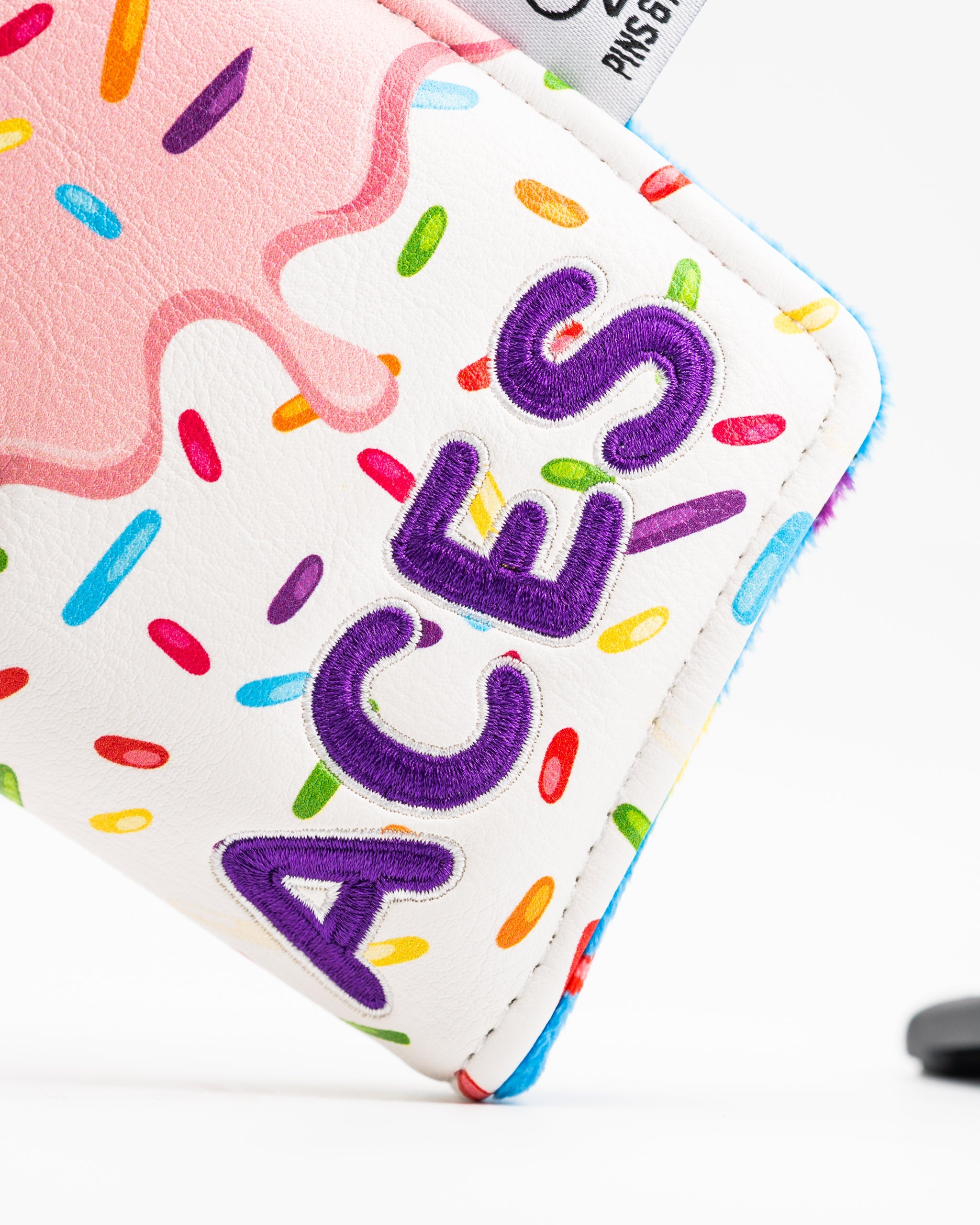 Colorful blade putter cover featuring a donut design with sprinkles and the word "ACES" in bold purple lettering.