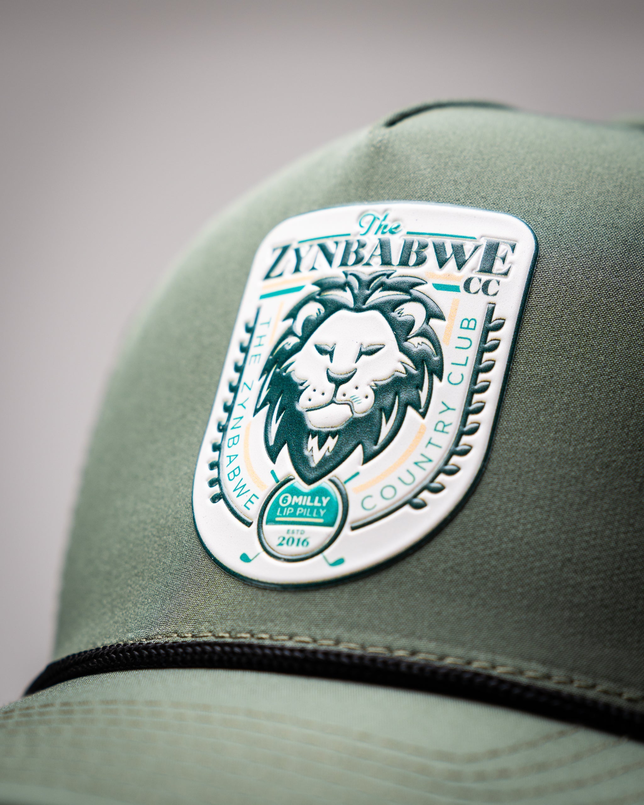 Olive perforated rope hat with Zynbabwe Country Club logo, featuring a snapback closure.