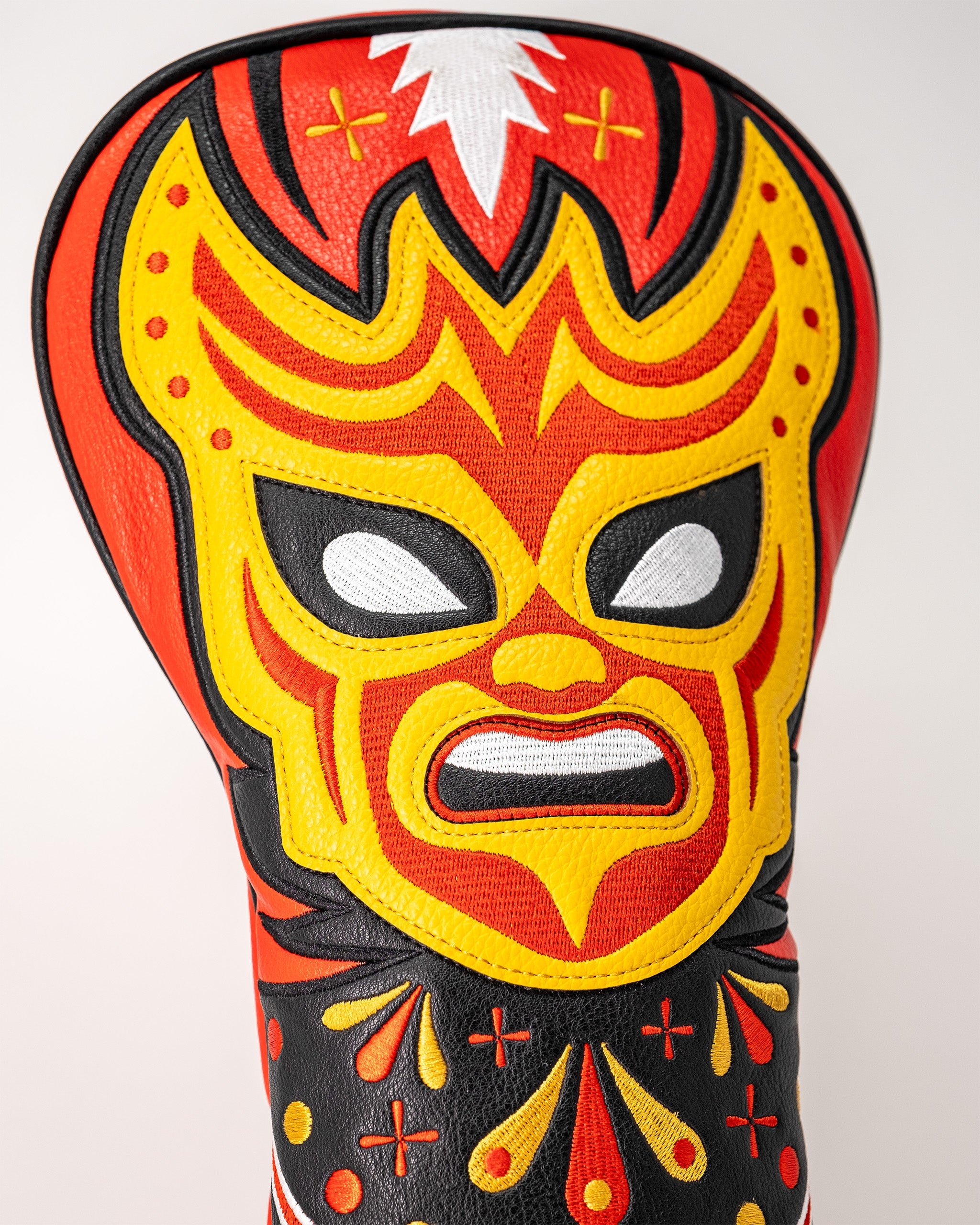 Colorful lucha libre mask-themed driver cover with a fierce, stylized mask design in red, yellow, black, and white.