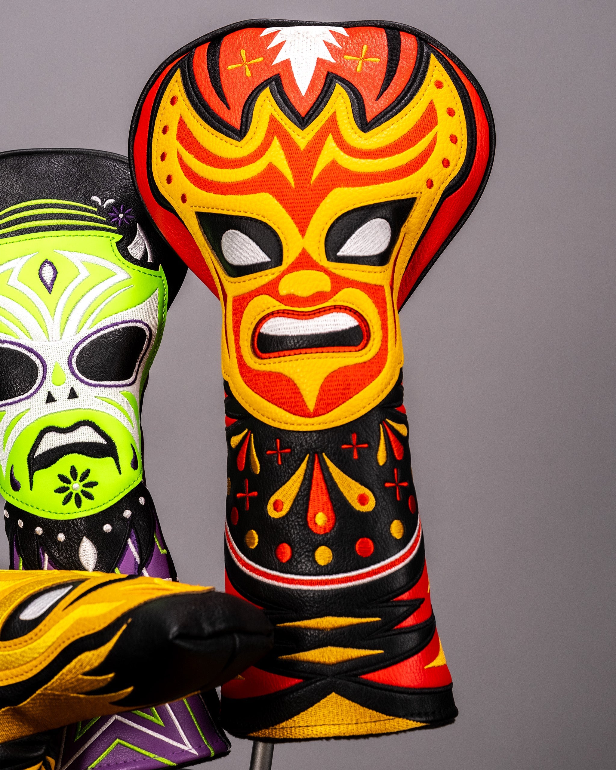 Colorful embroidered lucha libre mask with a fierce, fiery design in red, yellow, and black, resembling a traditional Mexican wrestler's headgear.
