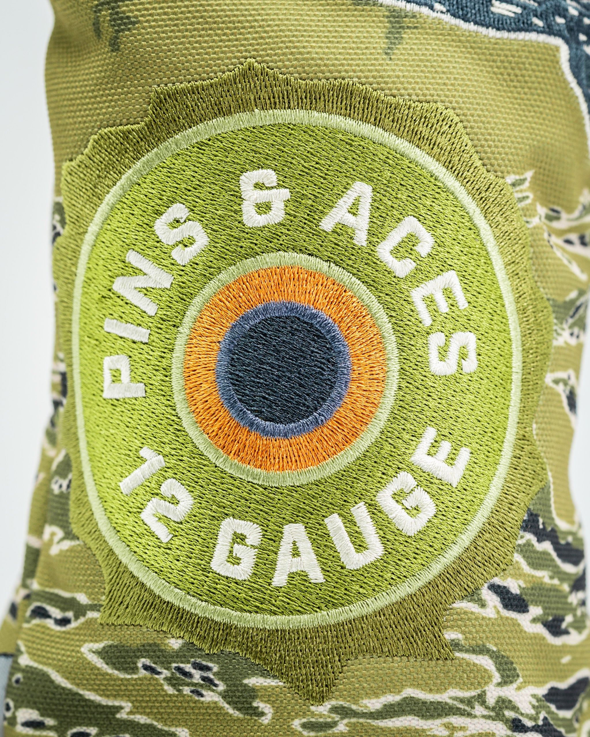 Camouflage driver cover featuring a vibrant embroidered logo with "Pins & Aces" and "12 Gauge" text for golfers.