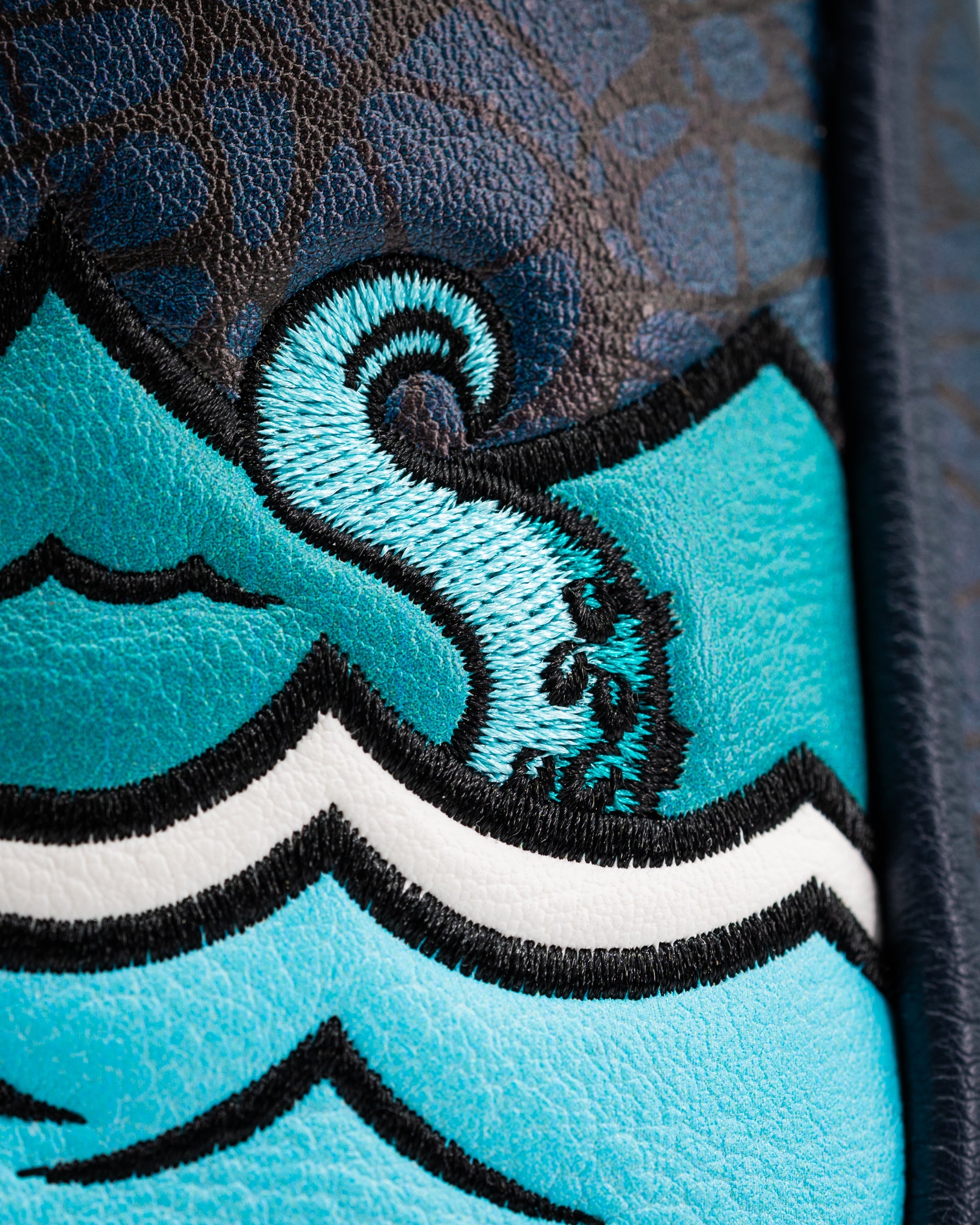 Close-up of the Kraken mallet putter cover featuring vibrant blue waves and intricate embroidered details.
