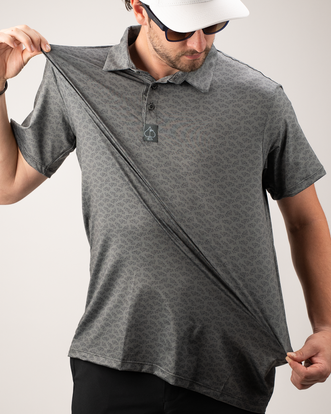 A golfer demonstrates the stretch of a gray patterned polo shirt, showcasing its comfort and fit.