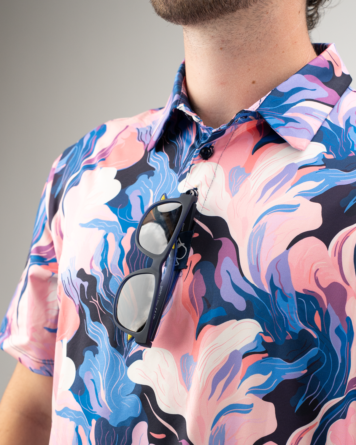 Men's Melting Floral golf shirt featuring vibrant pink and blue floral patterns, with sunglasses hanging from the collar.