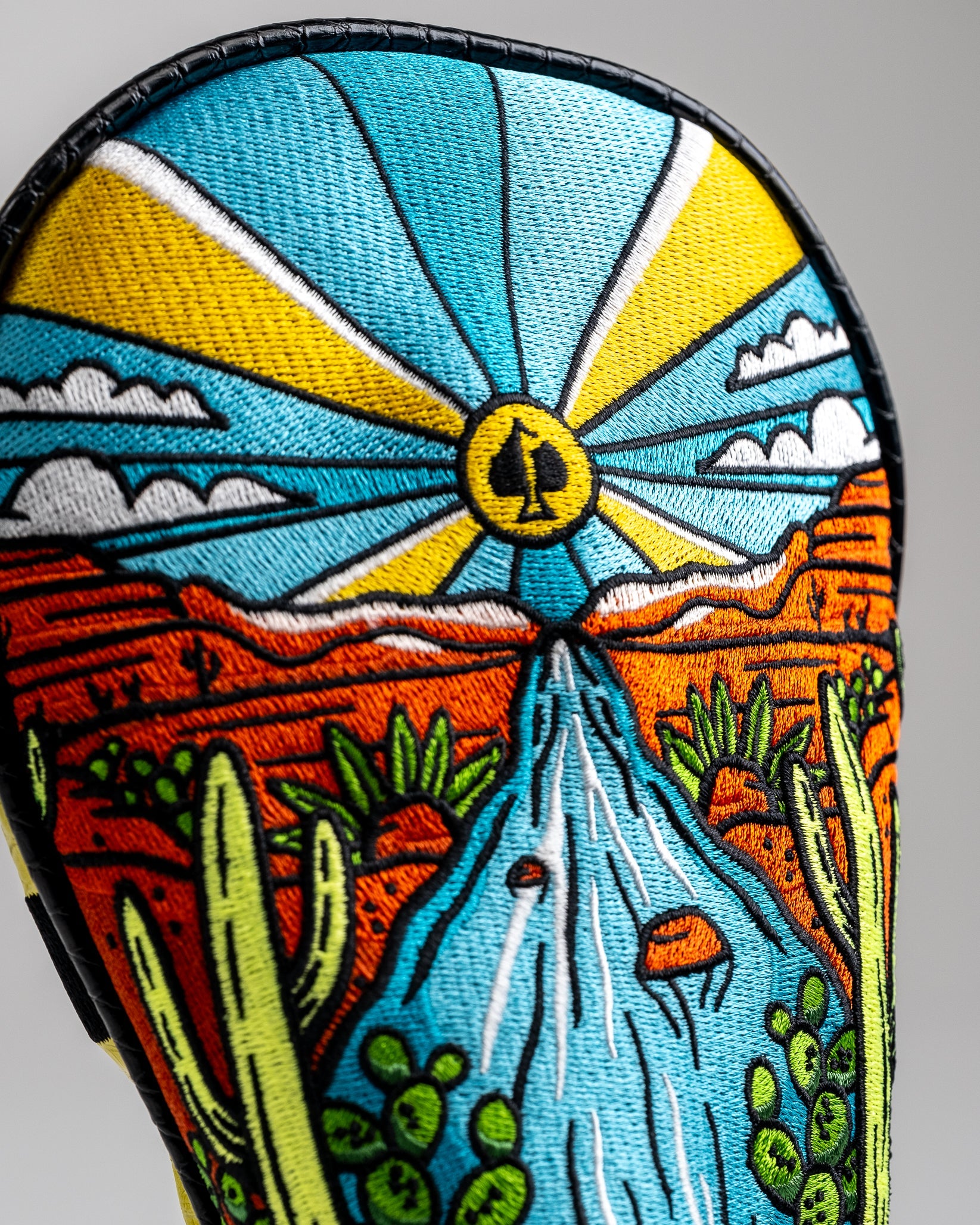 Colorful embroidered golf headcover with desert landscape, cactus, and sunburst design, perfect for bold, unique golf style.