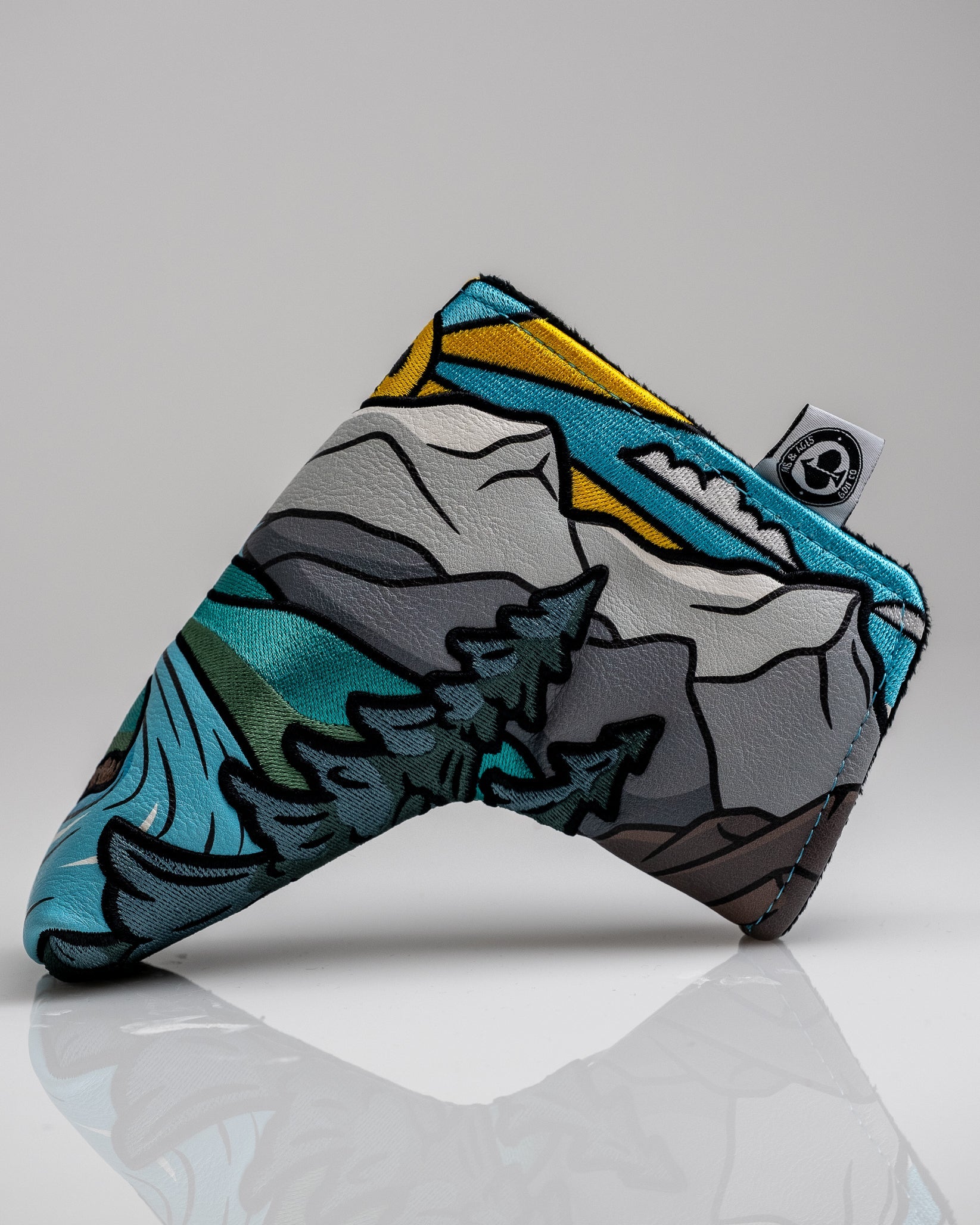 Colorful mountain and nature-themed golf headcover with bright blue, yellow, gray, and black accents for bold golfers.