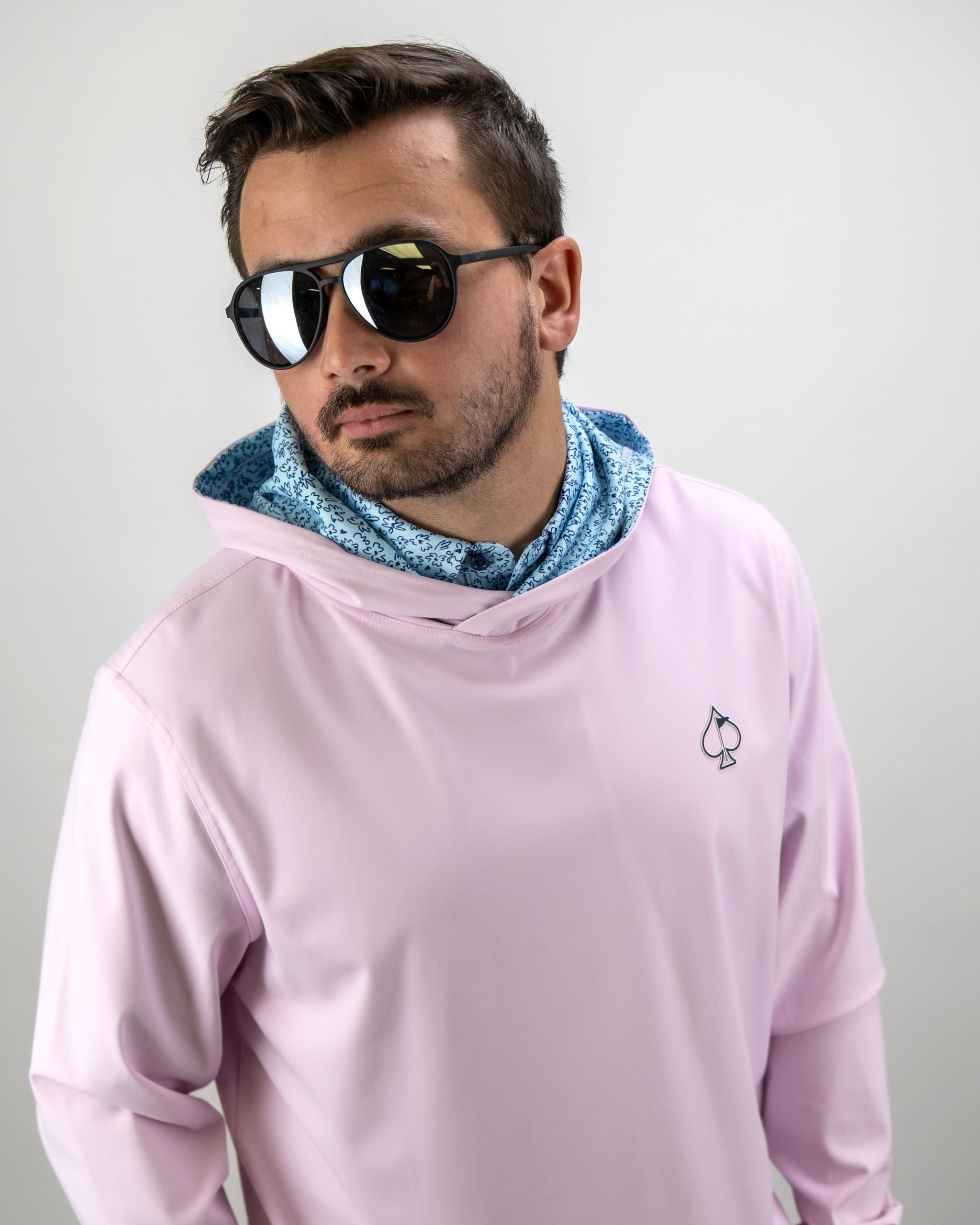 Stylish man wearing a pink performance golf hoodie with a flower doodle blue collar, showcasing a modern golf look.