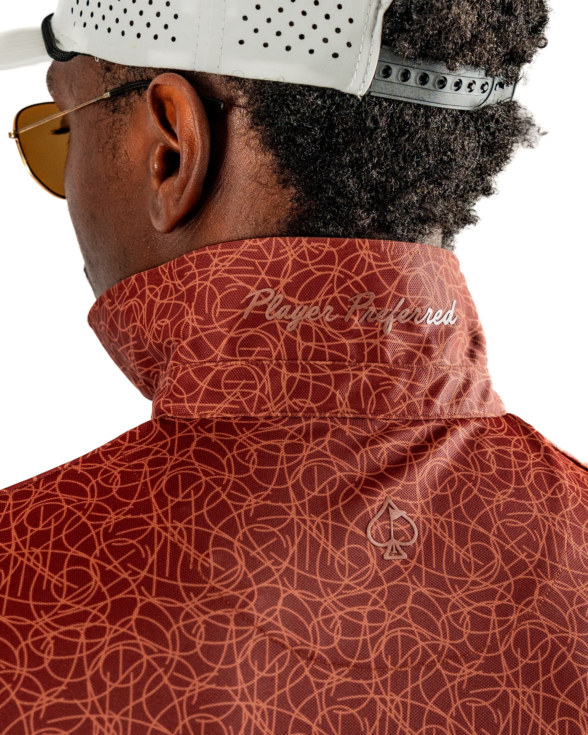Stylish golfer wearing a patterned red Filament jacket with a high collar and "Player Preferred" embroidery on the back.