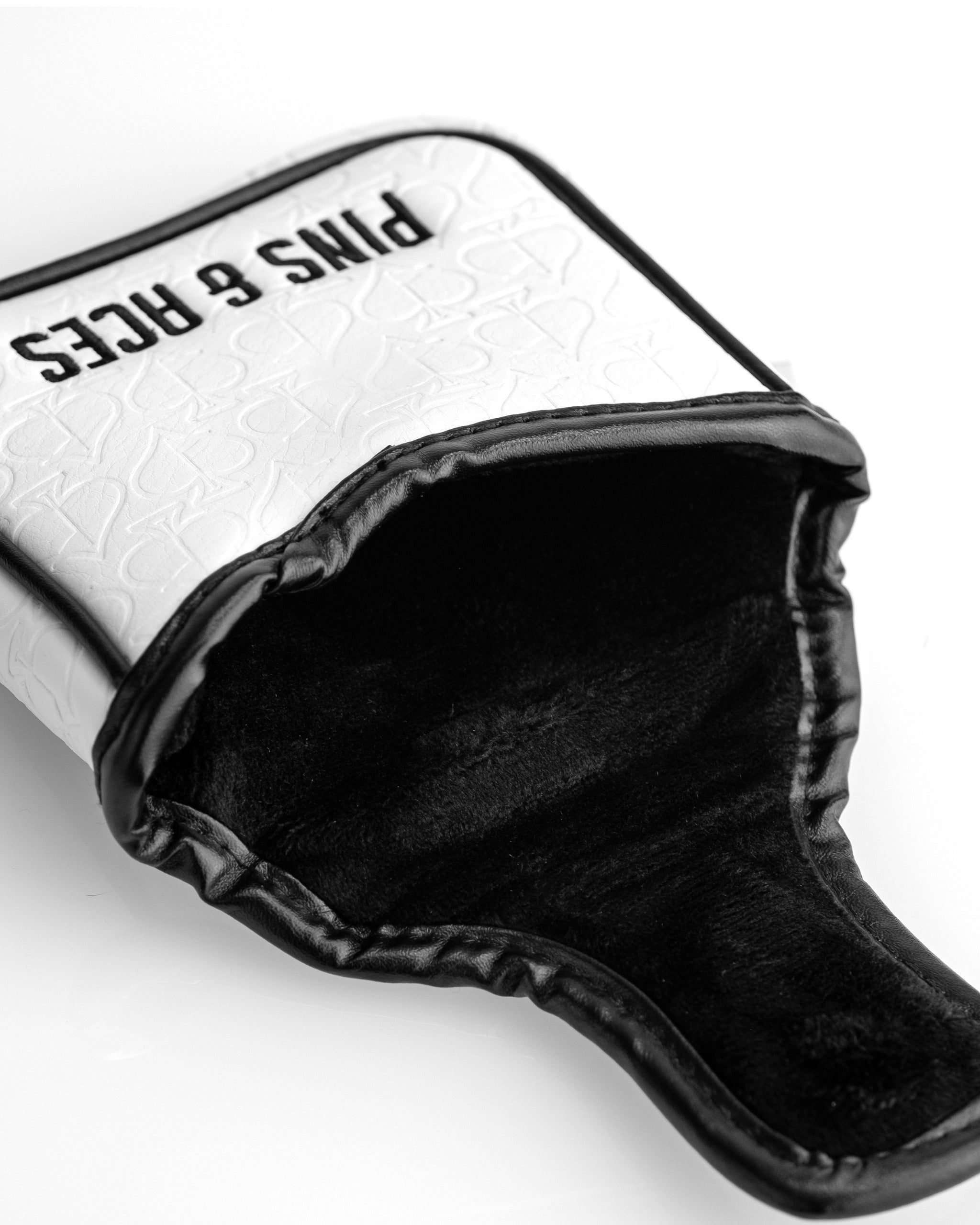 Black and white golf headcover with embossed logo, bold "PINS & RICHES" text, and unique, stylish design for standout golf...