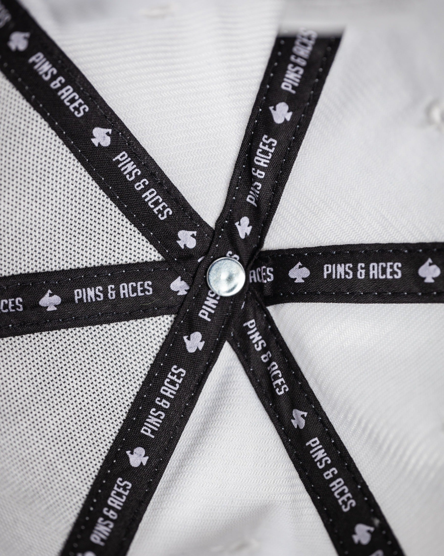 White Performance Spade Hat featuring a stylish interior design with branded black straps for golfers seeking bold style.