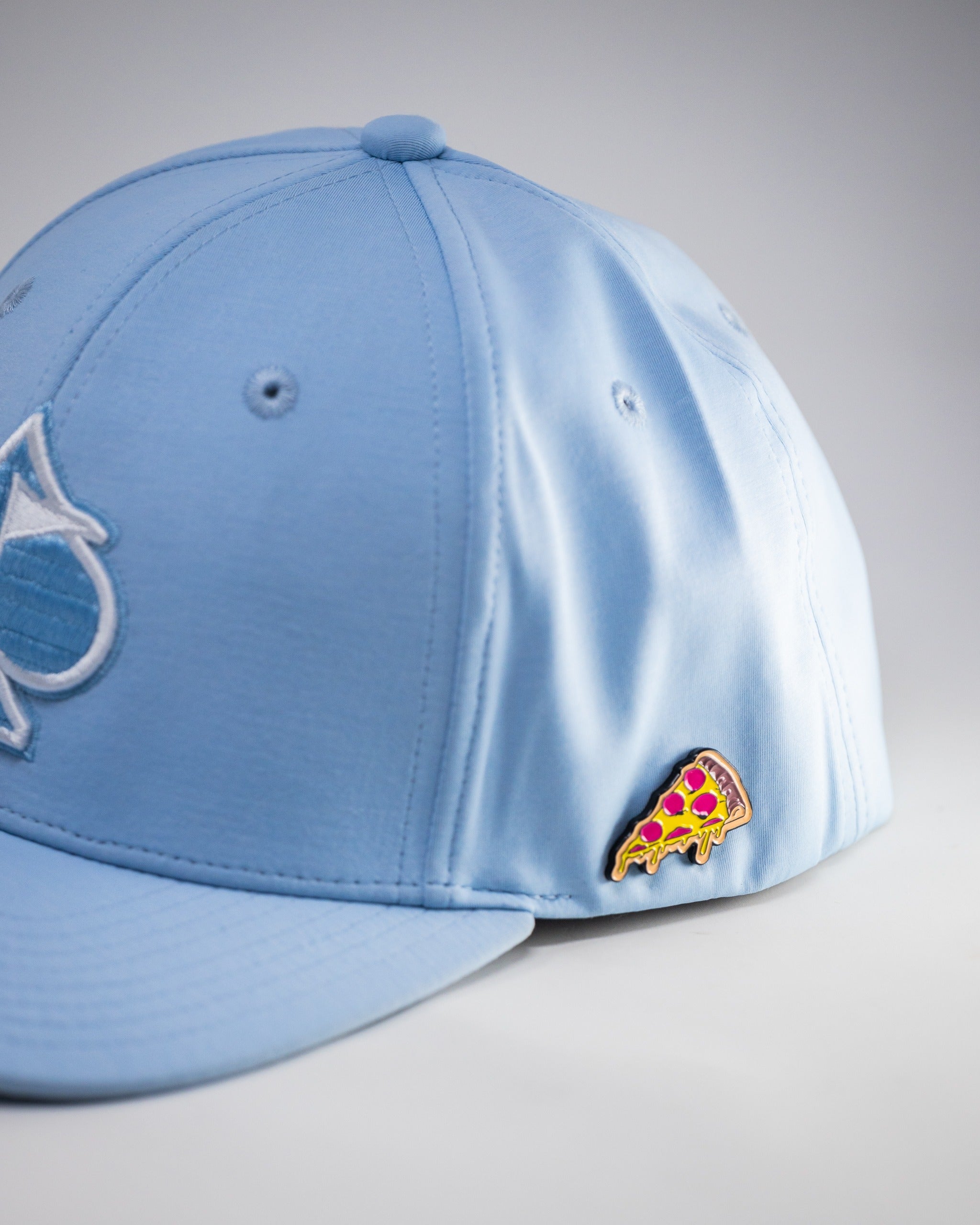 Carolina blue performance hat featuring a playful pizza pin, perfect for stylish golfers on the course.