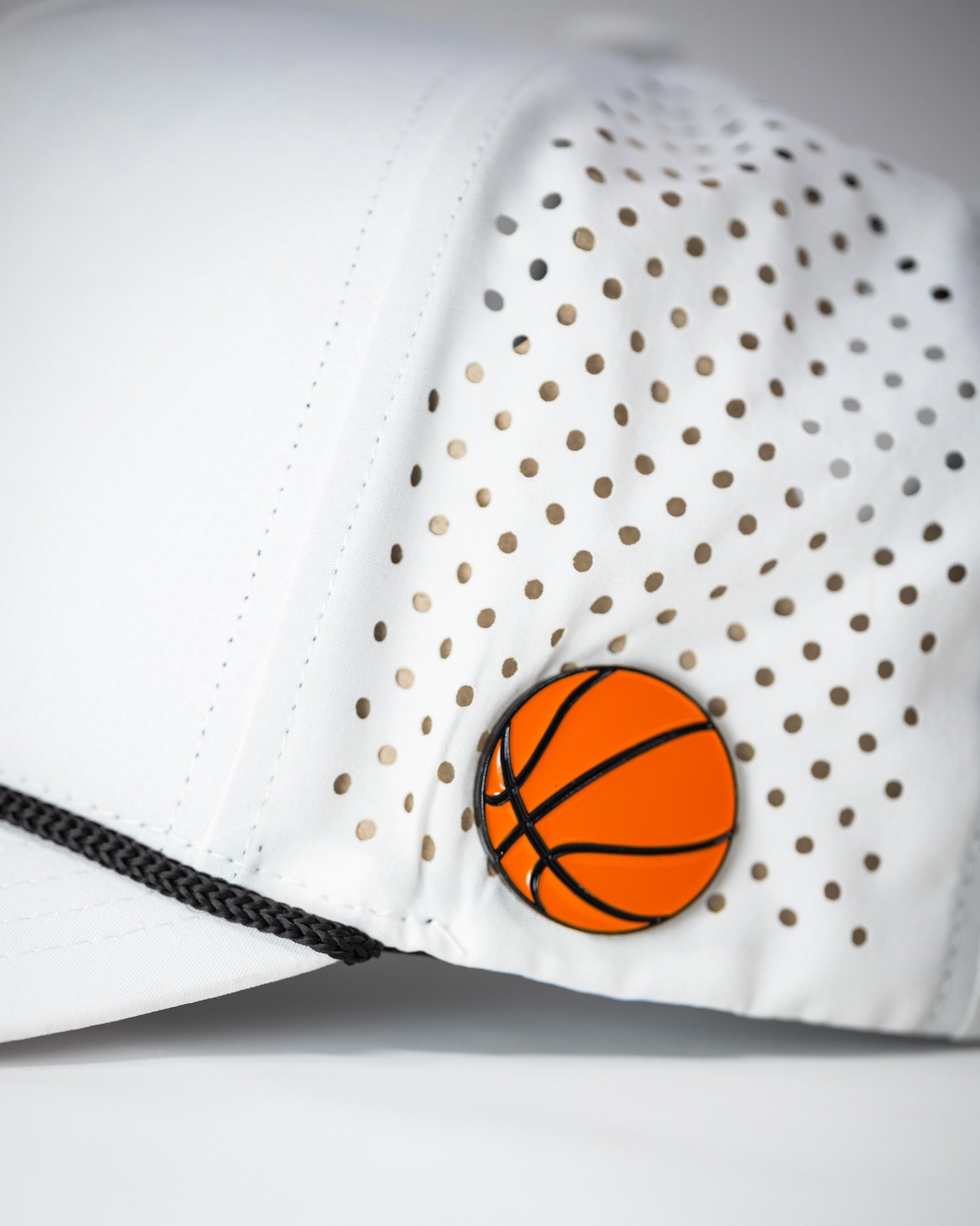White perforated rope hat featuring a stylish basketball logo, perfect for golfers seeking a bold accessory.