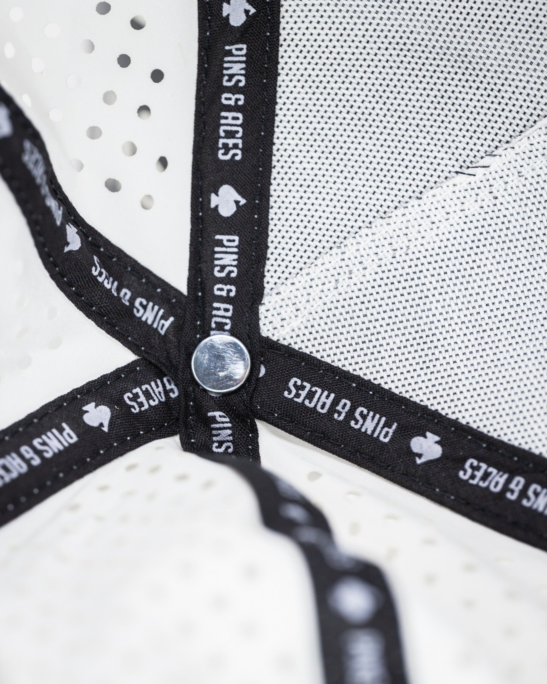 Perforated white rope hat featuring a stylish interior band with Pins and Aces branding for golfers.