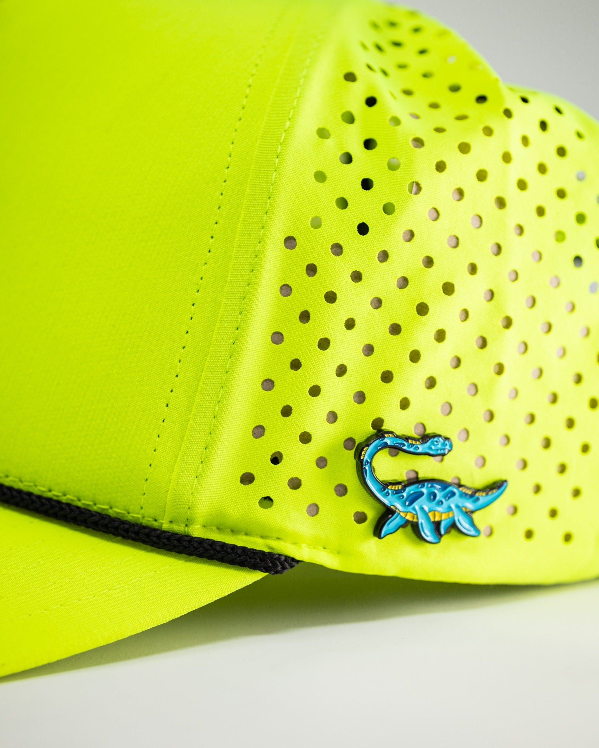 Highlighter yellow perforated rope hat featuring a unique blue dinosaur logo, perfect for bold golfers.