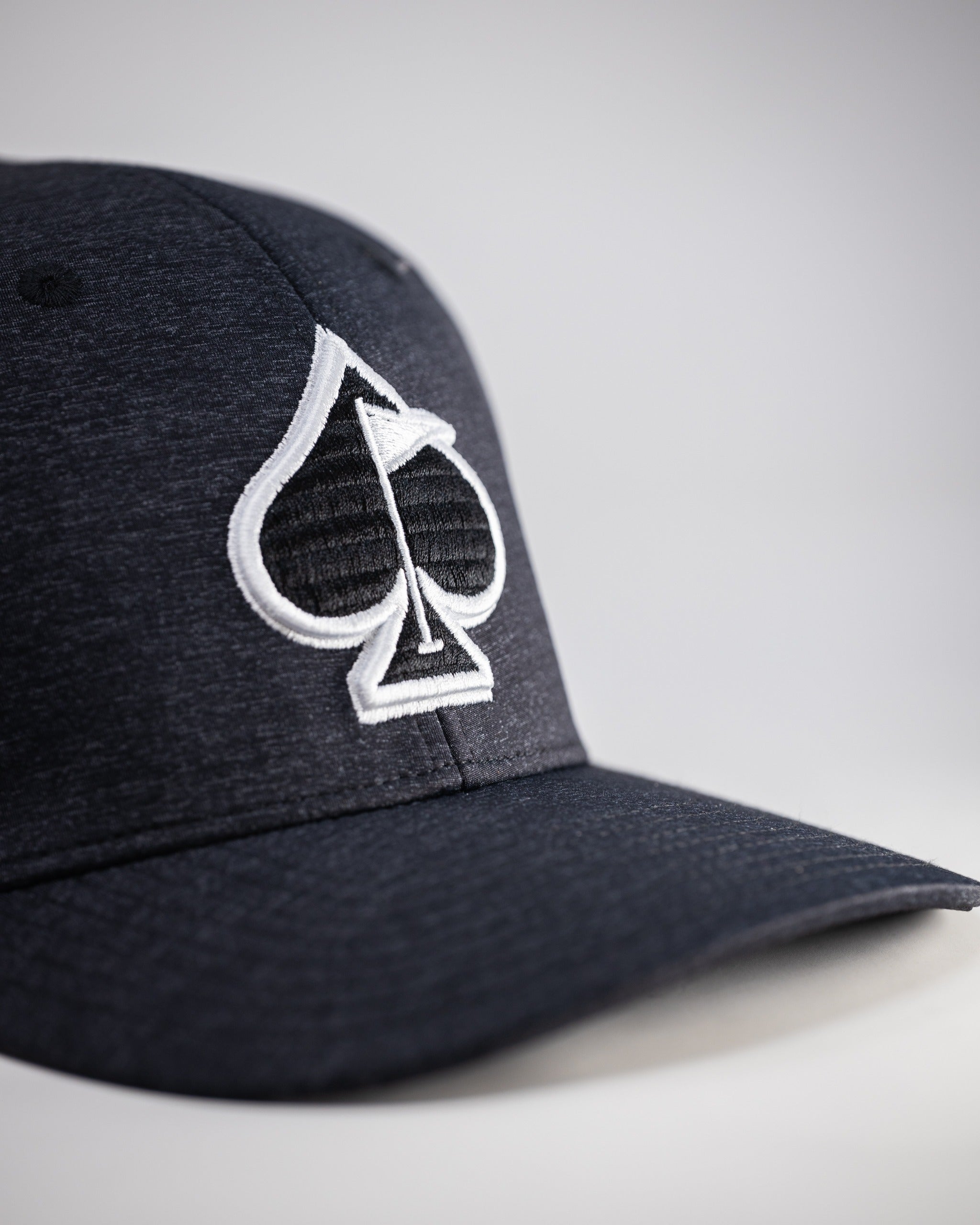 Charcoal performance hat featuring a bold spade logo, designed for golfers seeking style and comfort on the course.