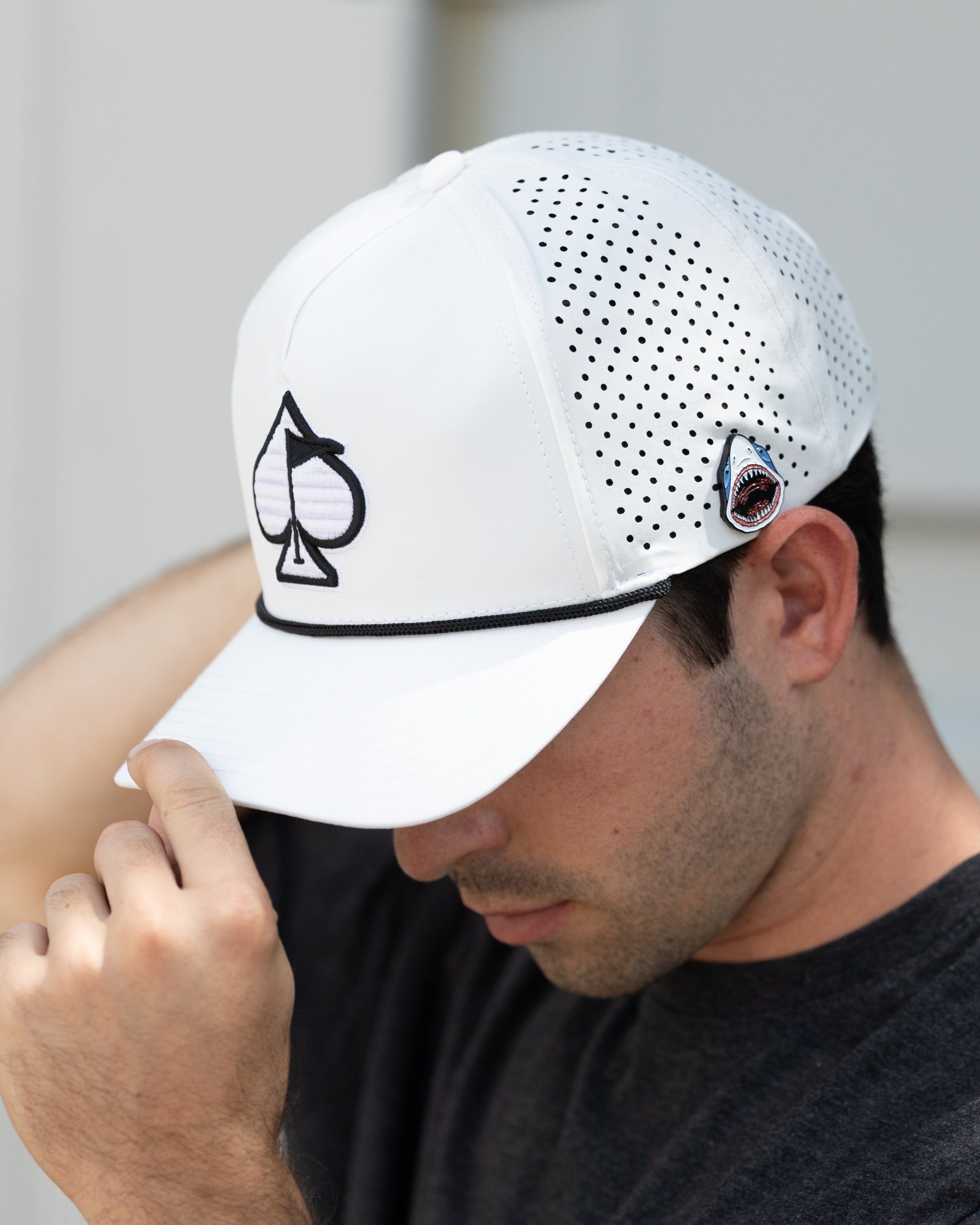 White Performance Spade Hat featuring a perforated design and embroidered logo, ideal for stylish golfers.