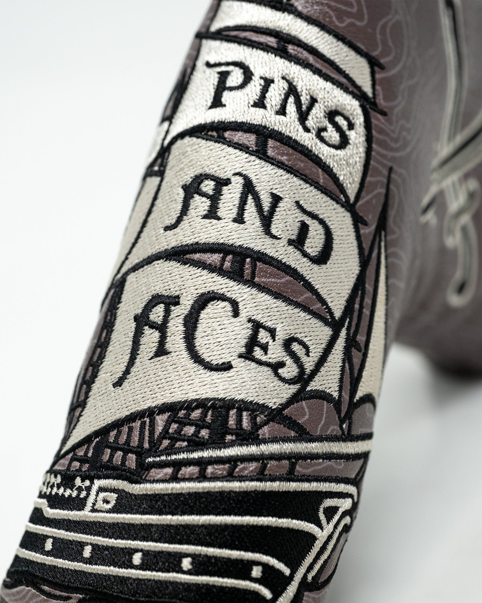 Bold pirate-themed blade putter cover featuring intricate ship design and "Pins and Aces" lettering for standout style.