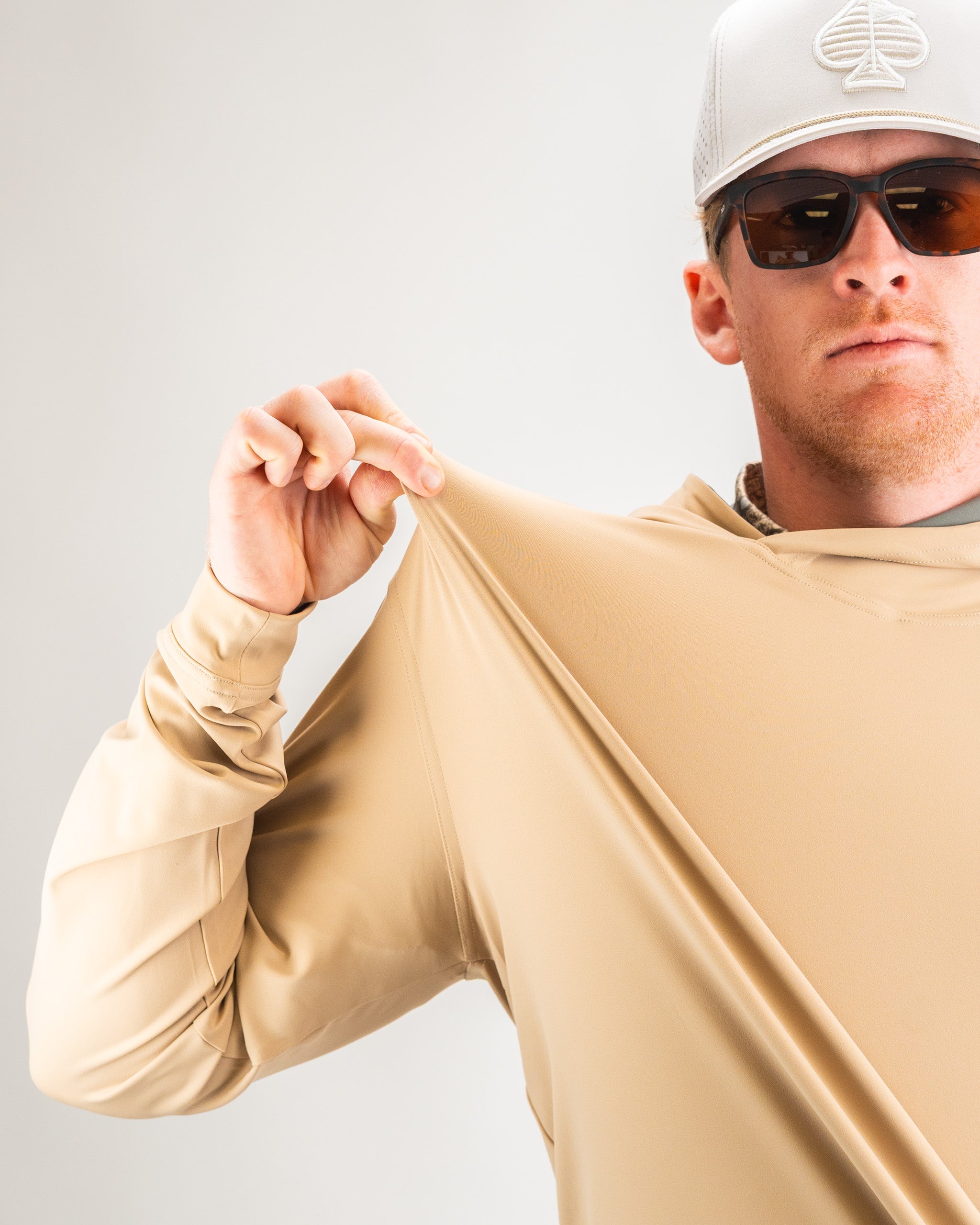 Performance golf hoodie in sand color, showcasing its stretchy fabric and relaxed fit, ideal for active golfers.
