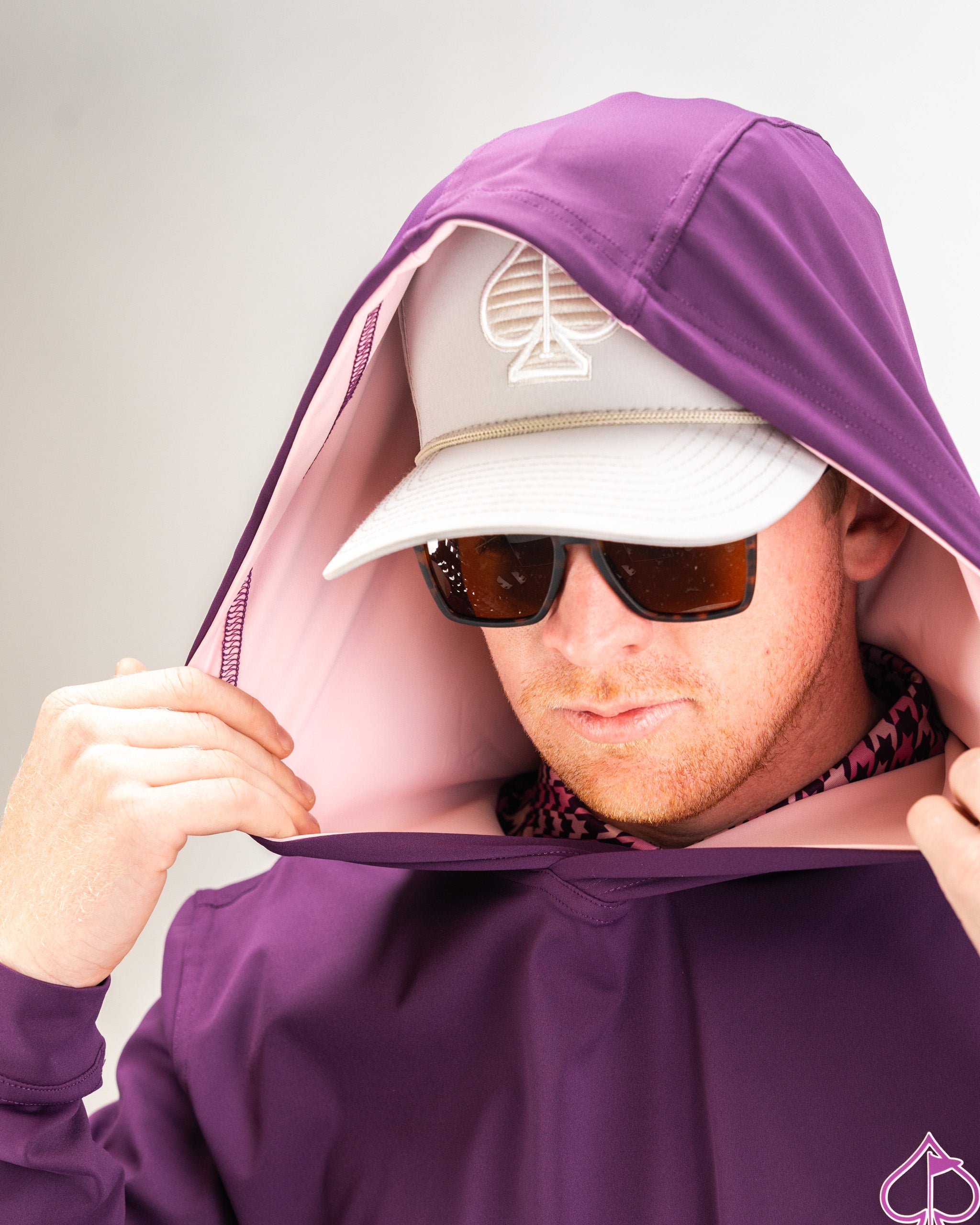 Performance golf hoodie in houndstooth raspberry, featuring a stylish hood and a golfer wearing sunglasses and a cap.