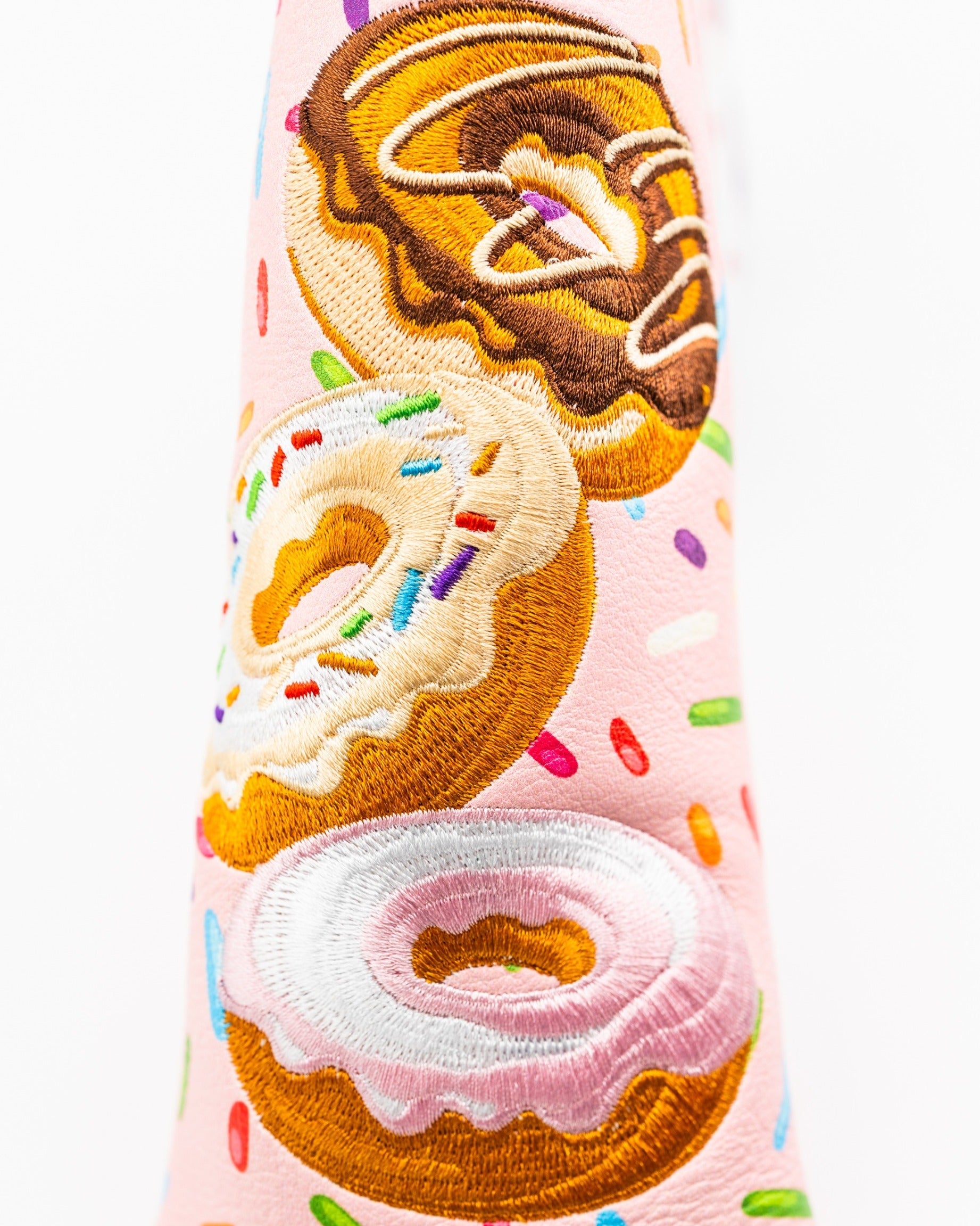 Colorful blade putter cover featuring three embroidered donuts with sprinkles on a pink background, perfect for stylish golfers.