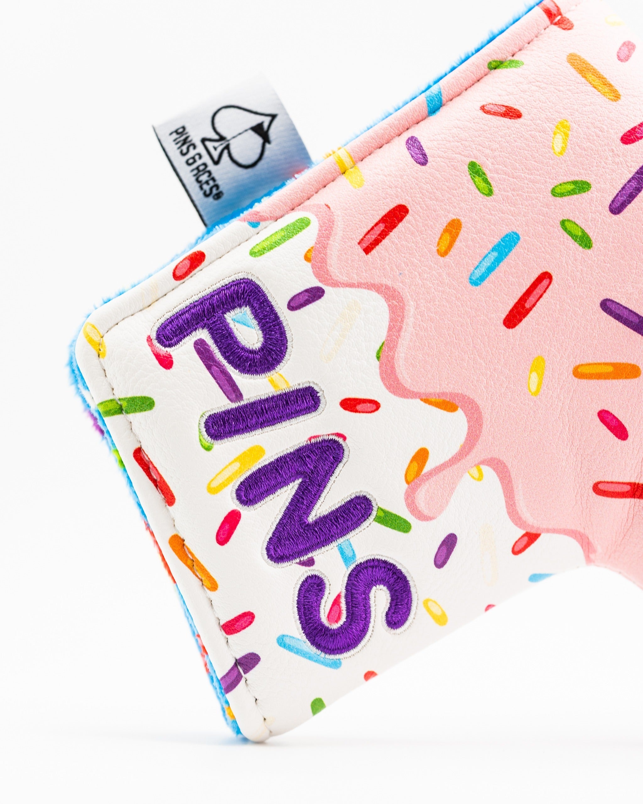 Colorful blade putter cover featuring a pink icing design with sprinkles and the word "PINS" prominently displayed.