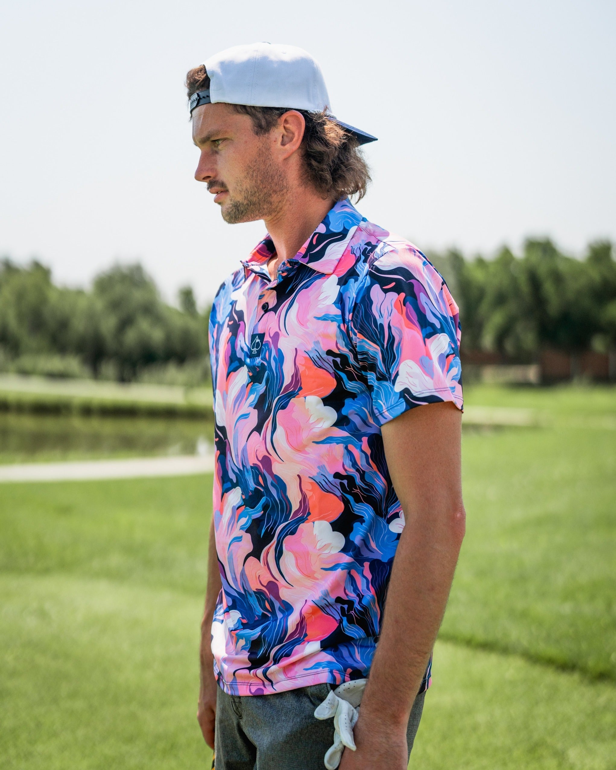 Bold golf polo featuring a melting floral pattern in vibrant pink, blue, and white, perfect for stylish golfers.