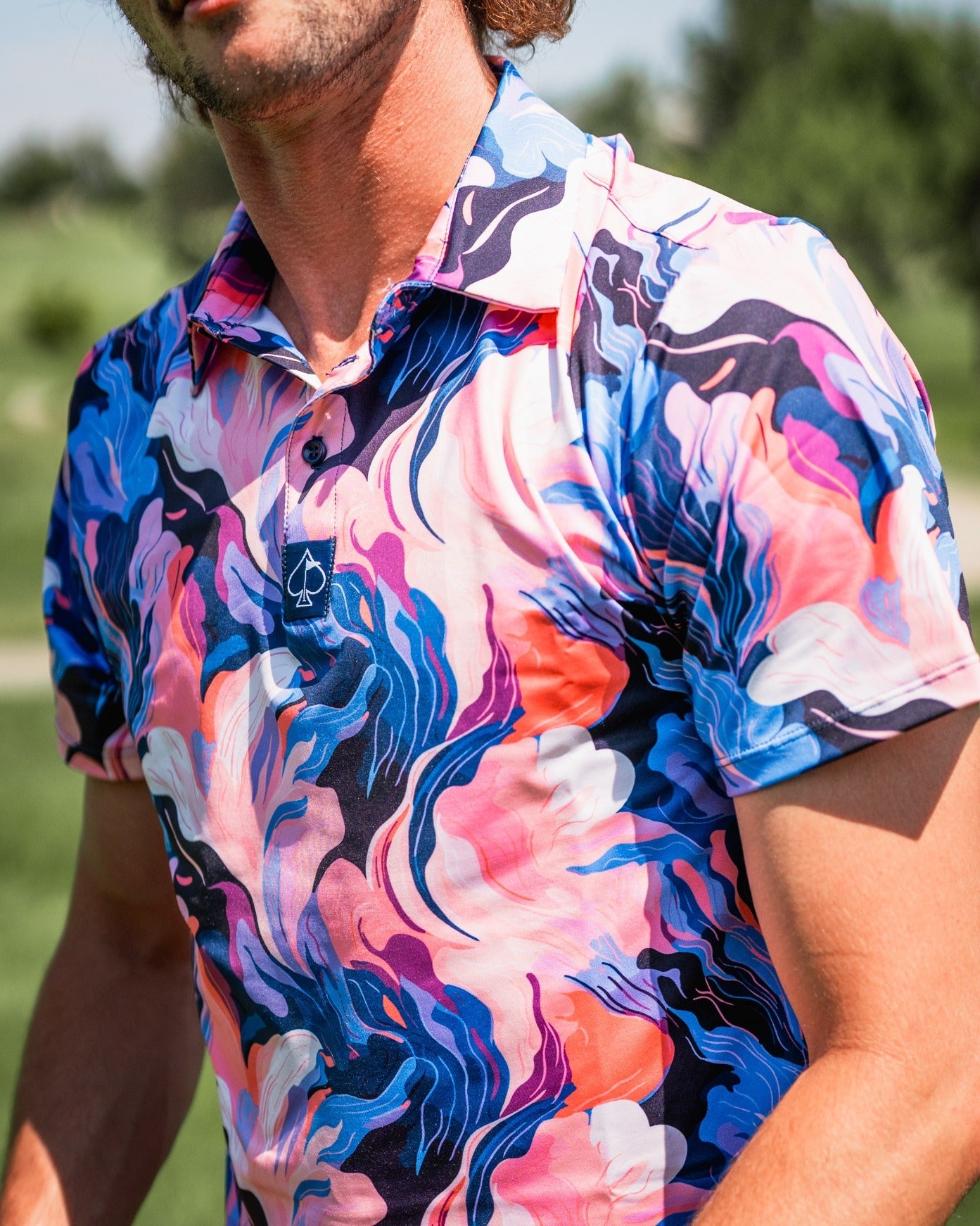 Bold golf polo featuring a vibrant melting floral pattern in pink, blue, and white, perfect for stylish golfers.