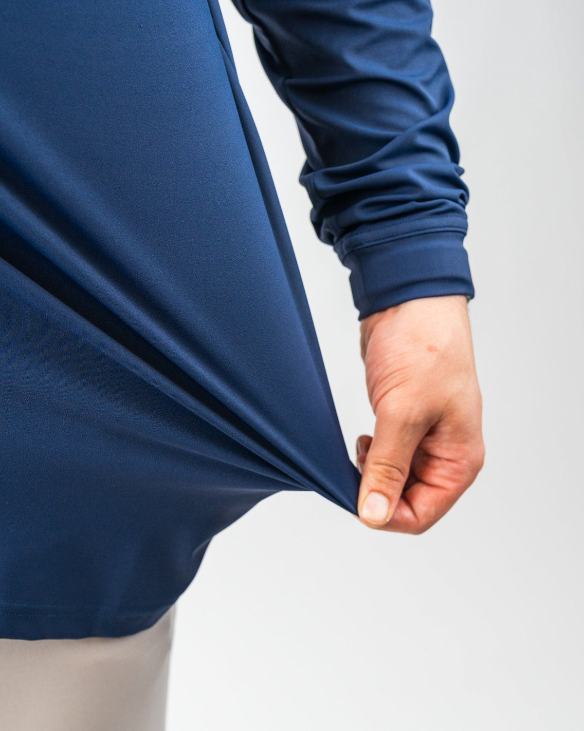 Close-up of a person pulling a navy blue, waterproof golf jacket, highlighting bold, vibrant color and sleek fabric design.
