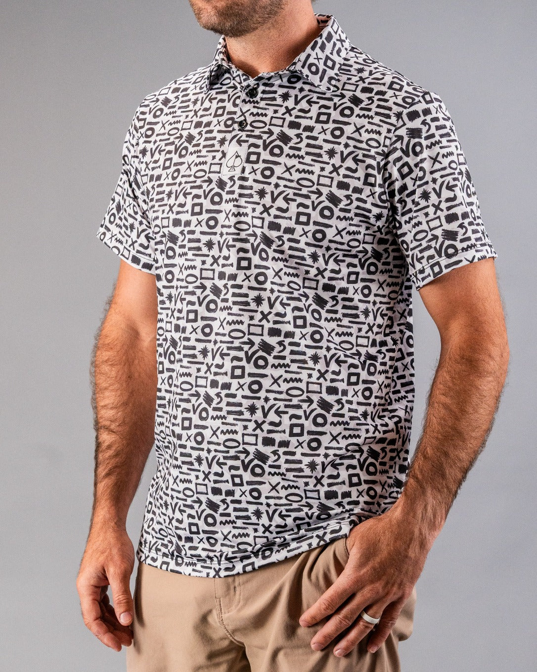 Black and white graphic patterned golf polo with bold geometric symbols, short sleeves, and a classic collar.