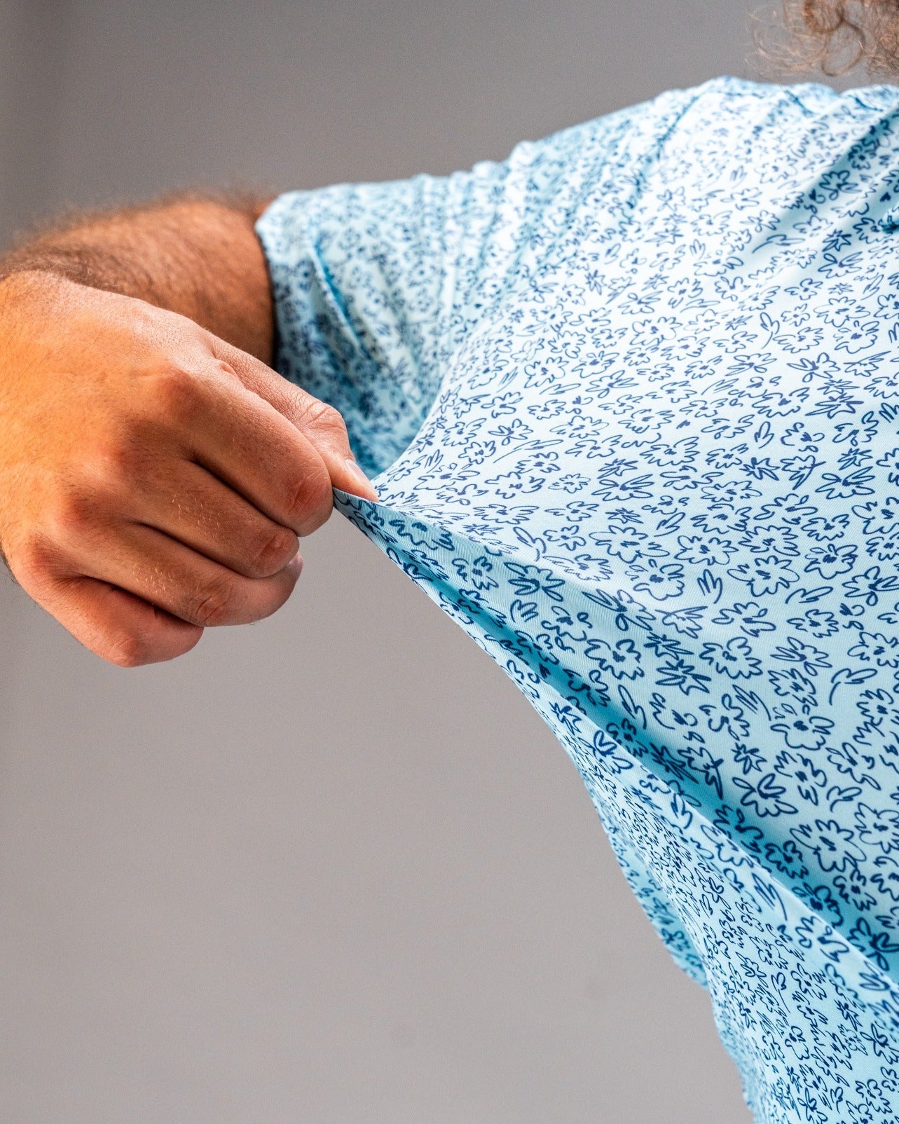 Light blue golf shirt featuring a playful flower doodle pattern, showcasing its stretchable fabric in action.