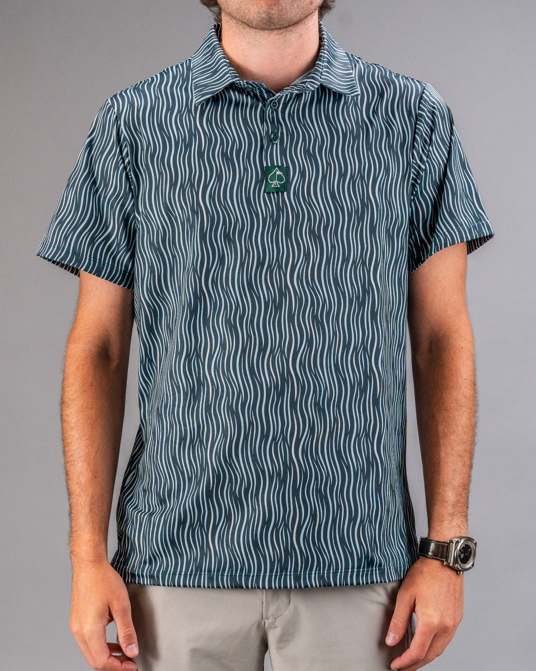 Men's golf polo shirt with a wavy blue and white pattern, classic collar, and green logo tag, perfect for bold golf style.