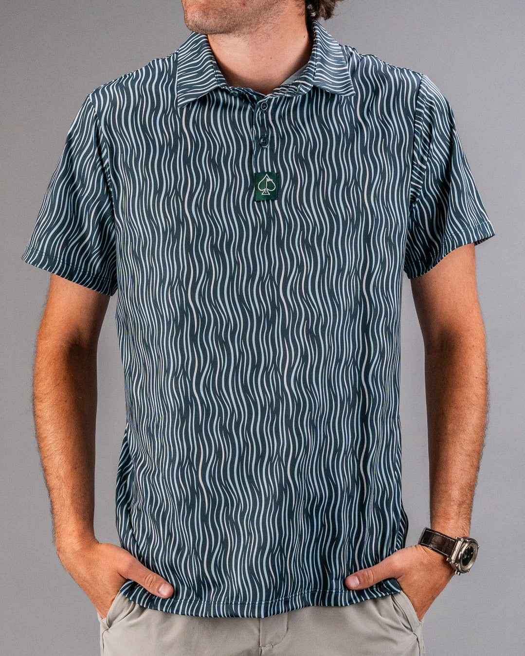 Bold blue and white wavy patterned golf polo with a green spade logo on the collar, perfect for standout style on the course.
