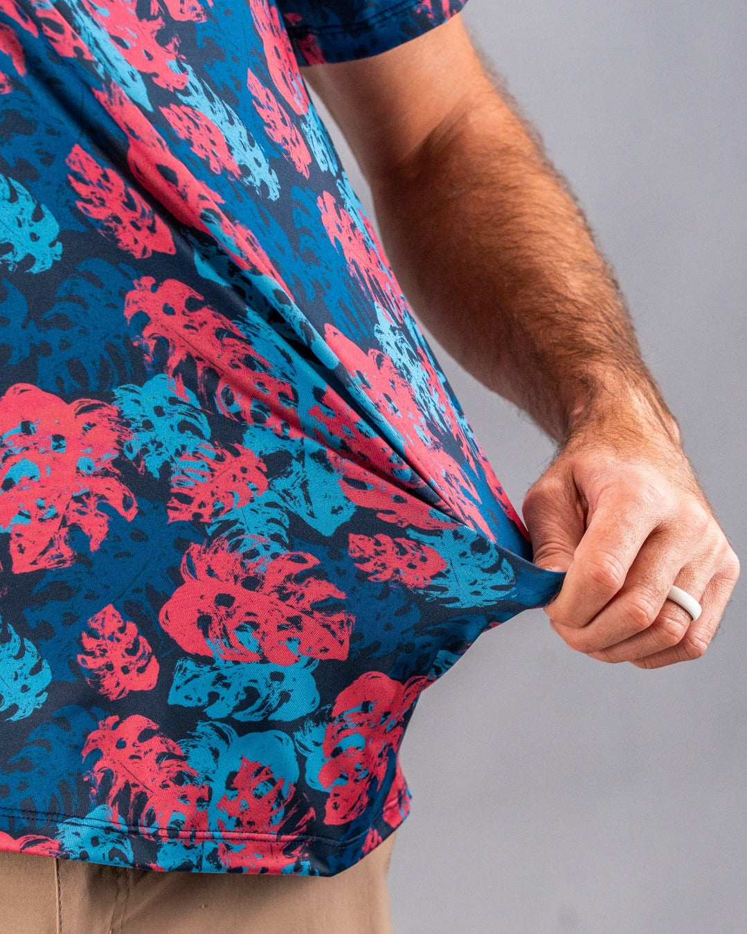 Close-up of a colorful golf shirt with pink and blue tropical leaf pattern, highlighting bold, unique style for standout g...