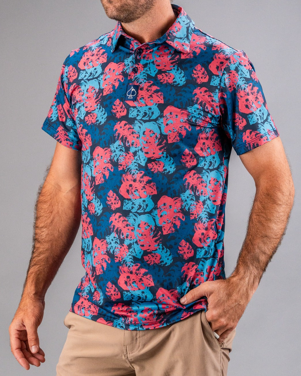 Men's vibrant tropical print golf shirt with pink and blue leaf patterns, short sleeves, and a collar.