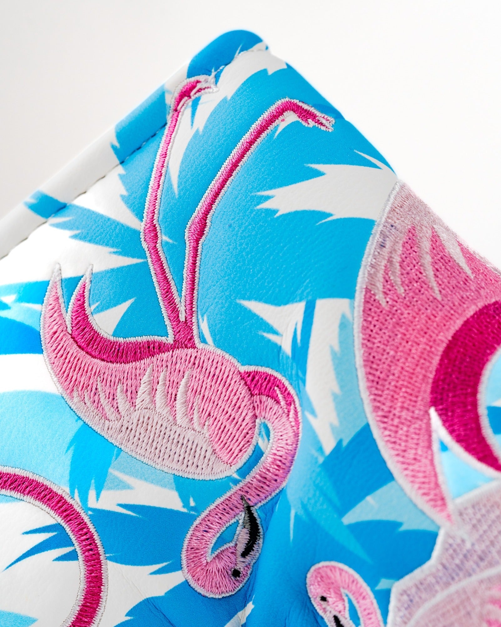 Vibrant blue blade putter cover featuring embroidered pink flamingos, perfect for adding style to your golf game.