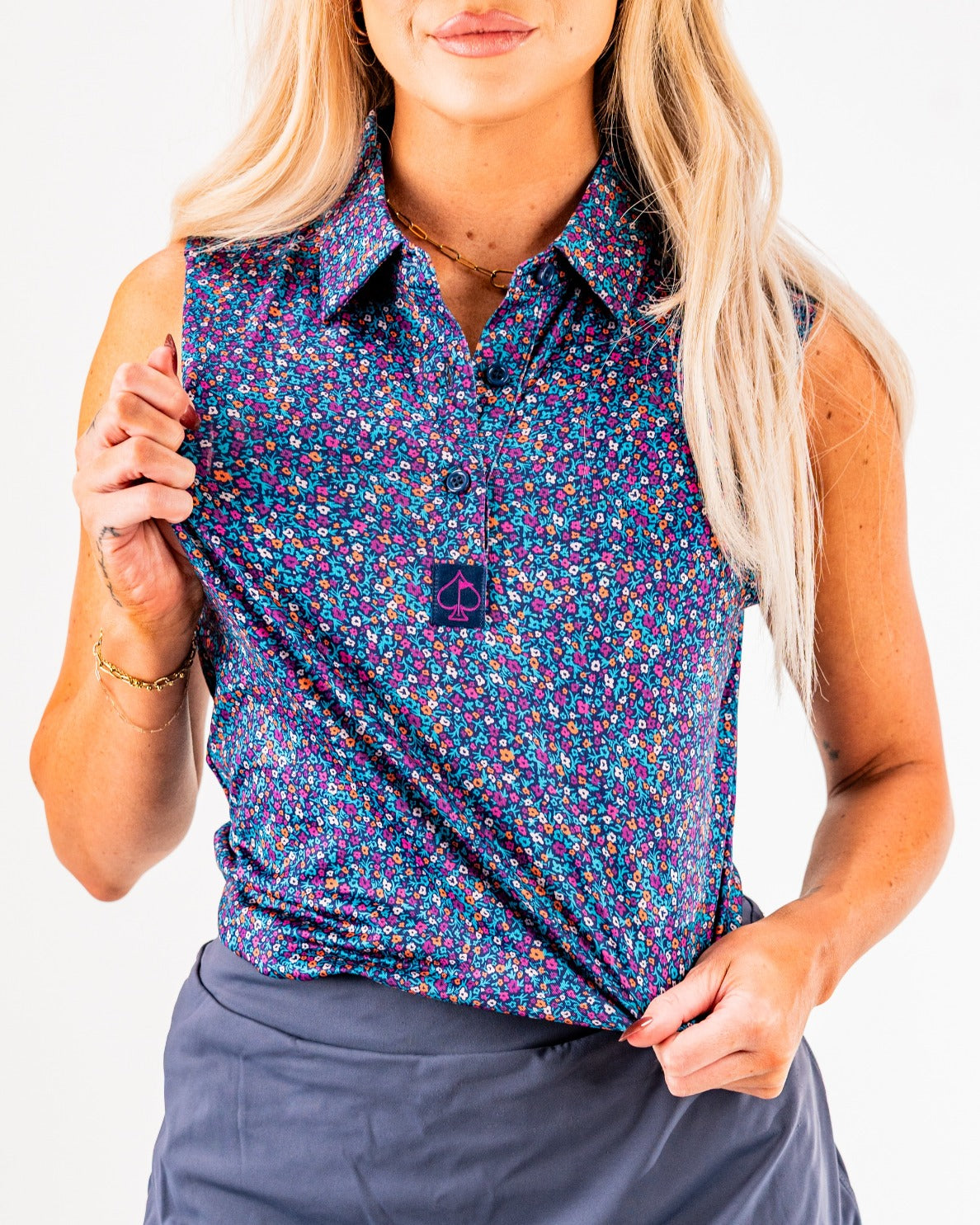 Women's sleeveless lavender floral golf shirt featuring a button-up design and a stylish logo on the front.